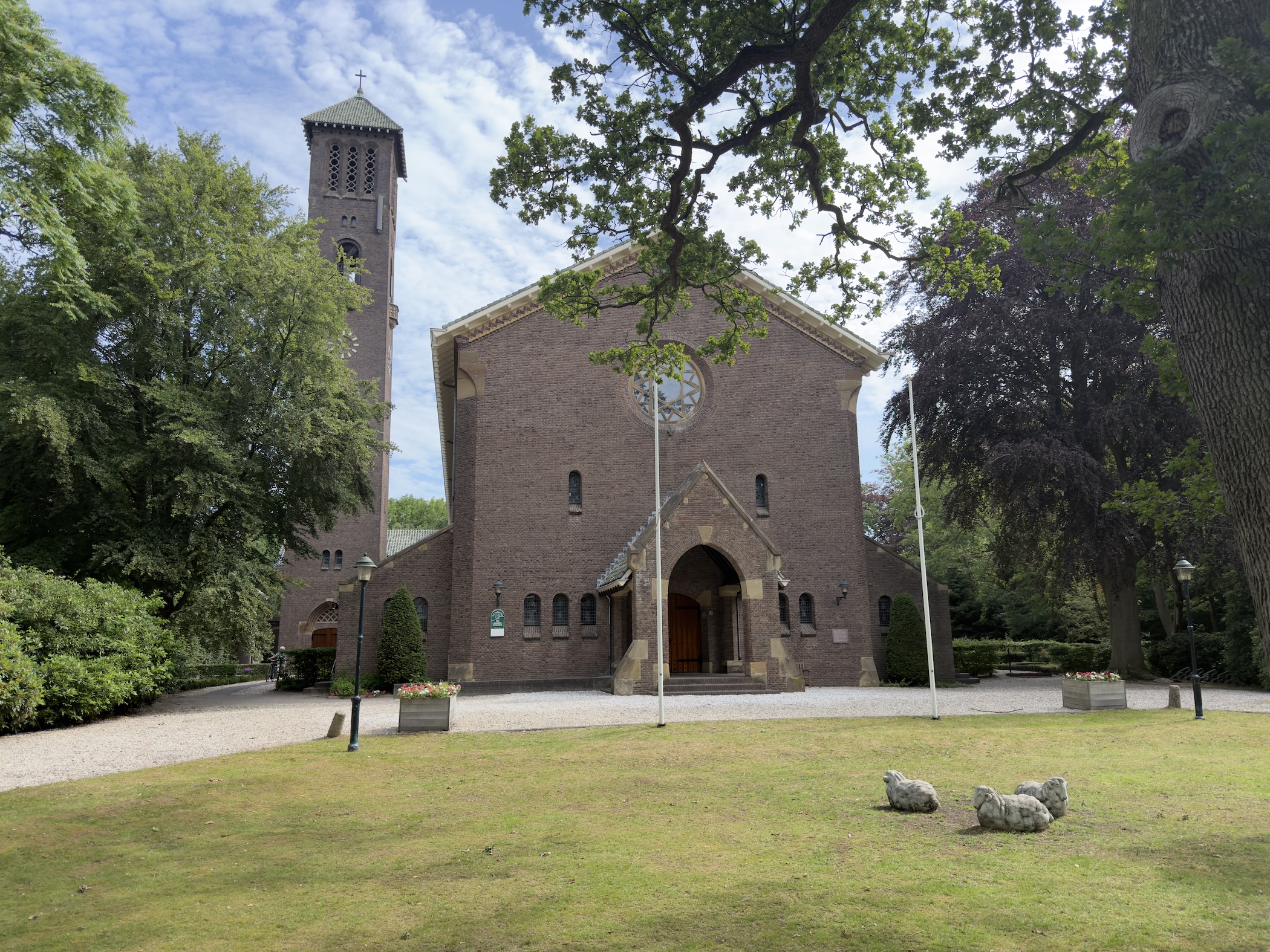 Brick church with a square tower and arched entrance set on a grassy lawn.