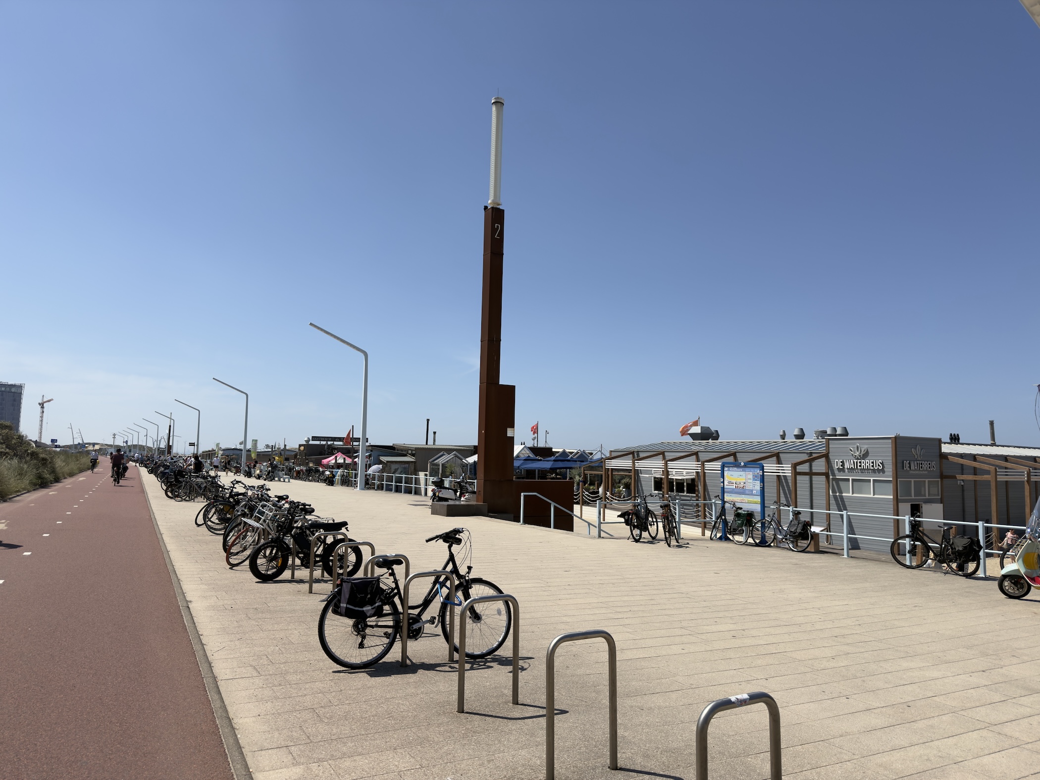 Bicycles parked along the promenade beside the rust-clad Waterreus beach pavilion and tower.
