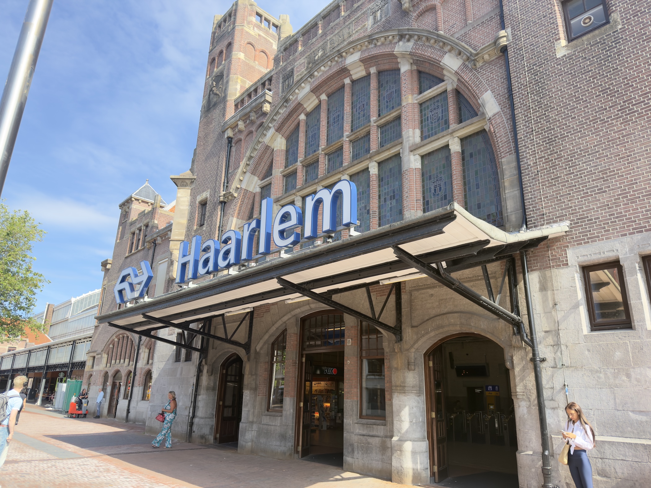 The ornate brick facade of Haarlem railway station under a bright blue sky.