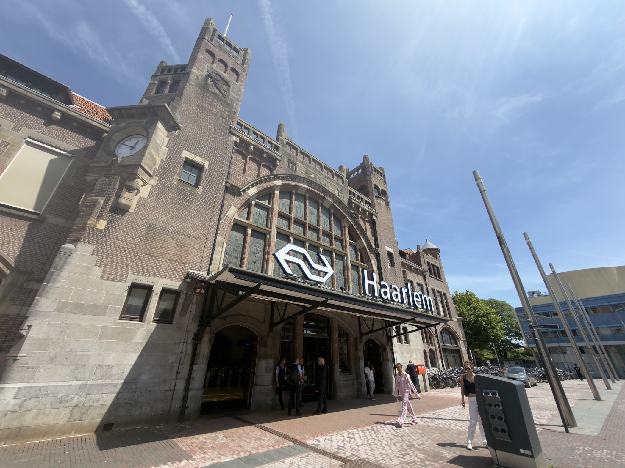 The brick Art Nouveau facade of Haarlem railway station under a blue sky.