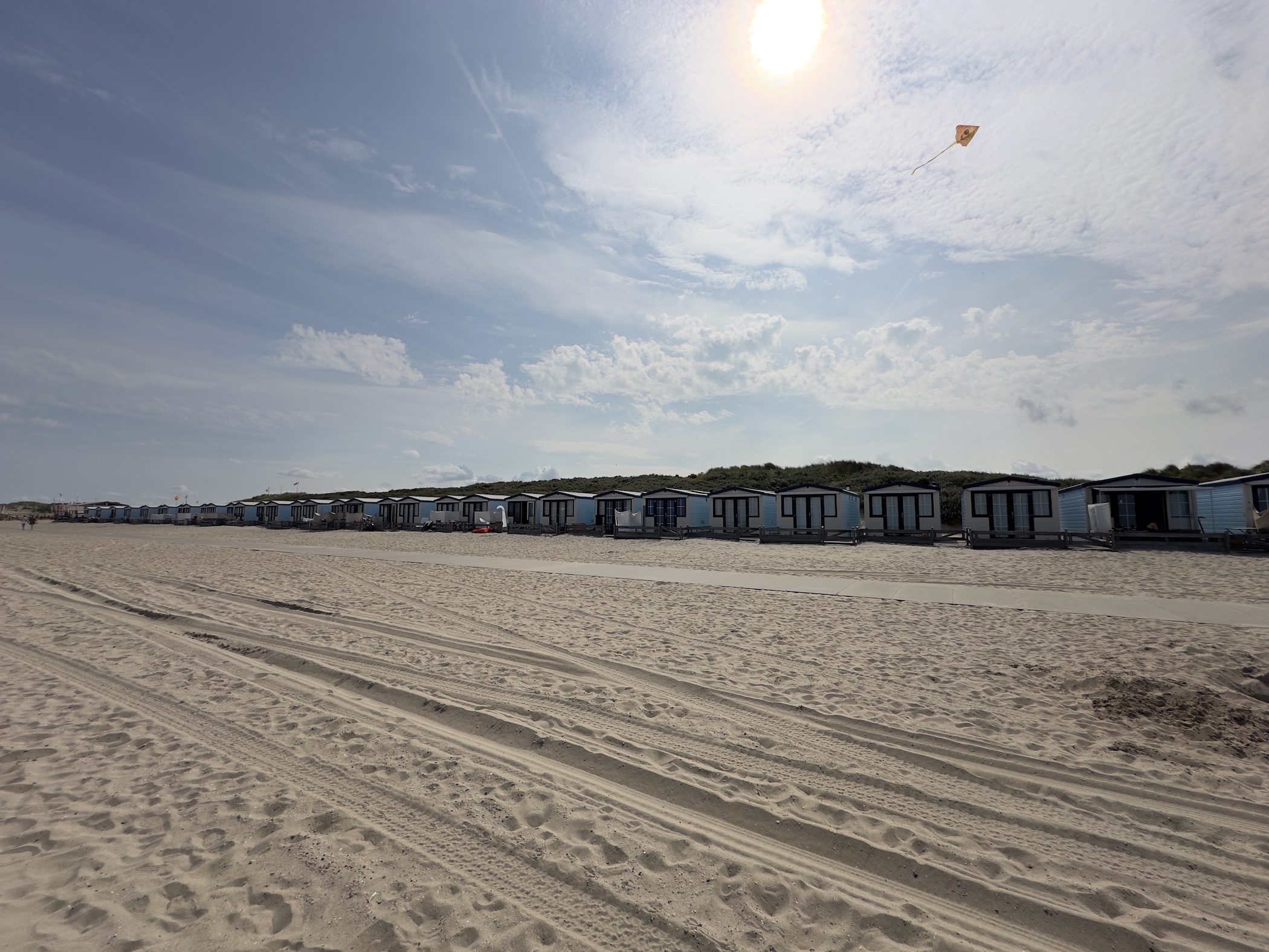 Beach with houses in the background and a kite in the sky