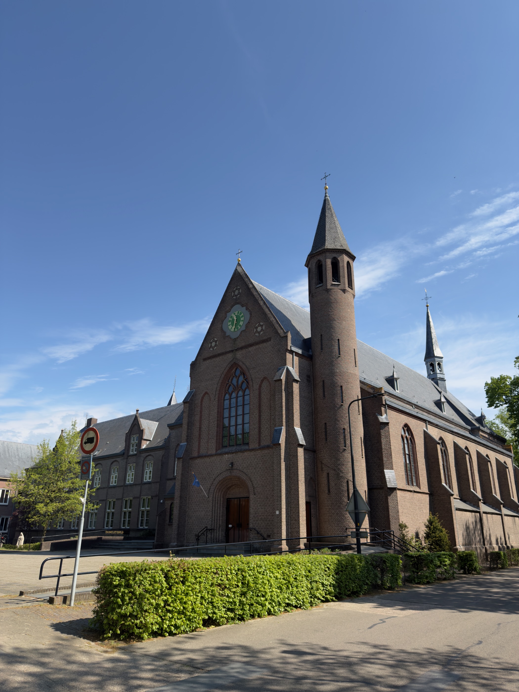 Front facade of the Carmelite monastery church showing the clock and steeple under blue sky