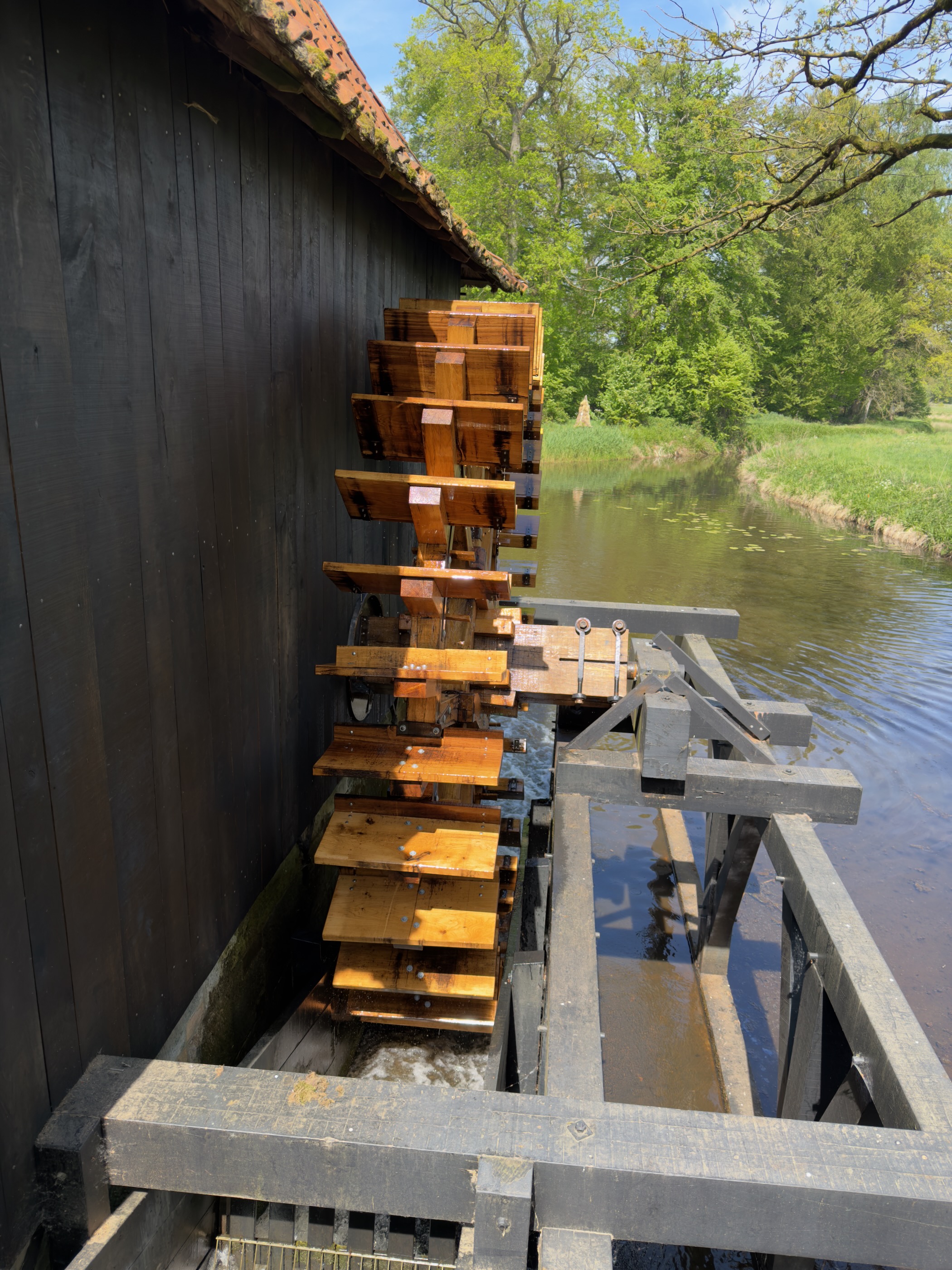 Close side view of the wooden water mill wheel with sluice over the canal