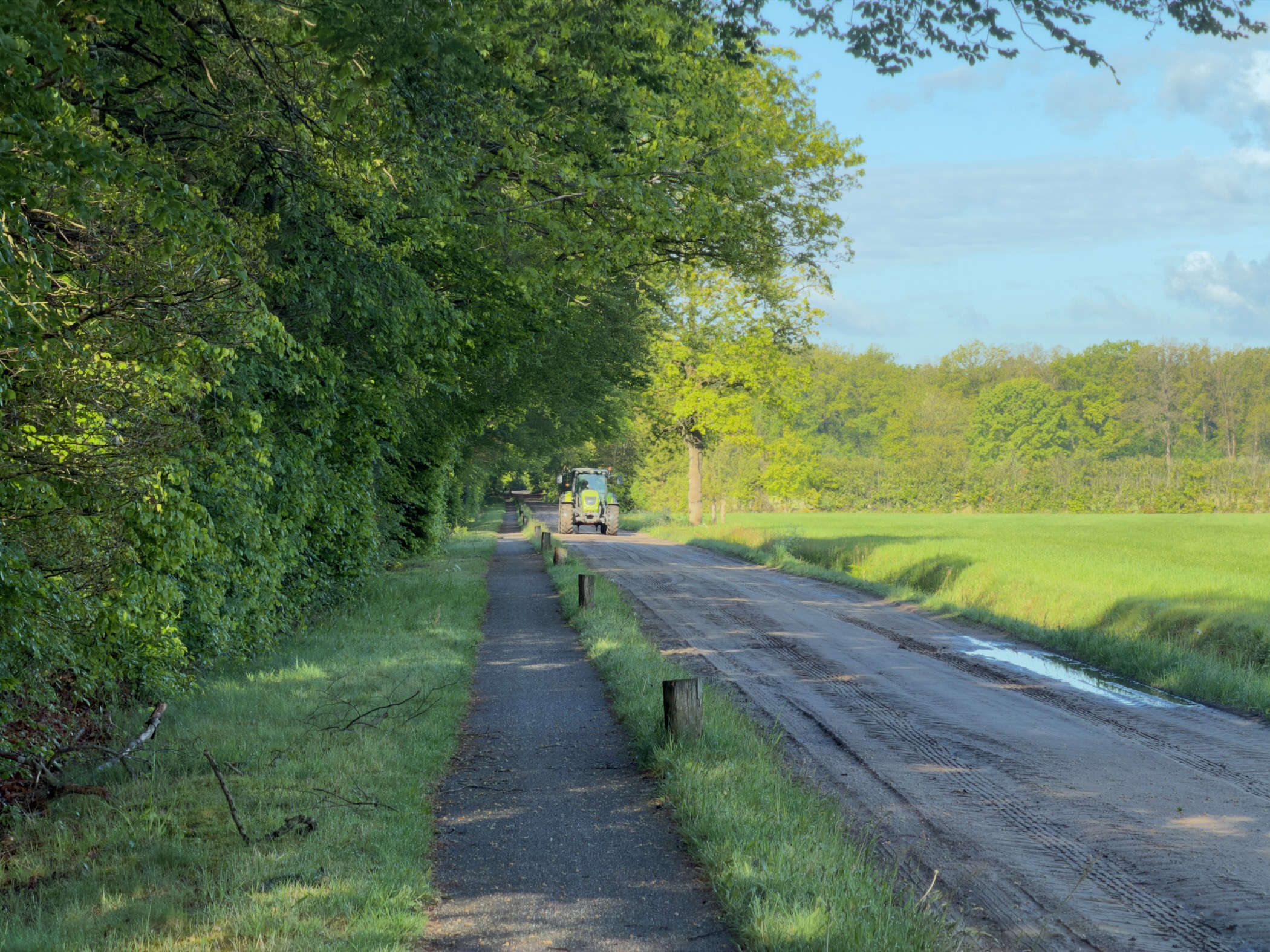 Cycle path beside a country road with a green tractor approaching in the distance