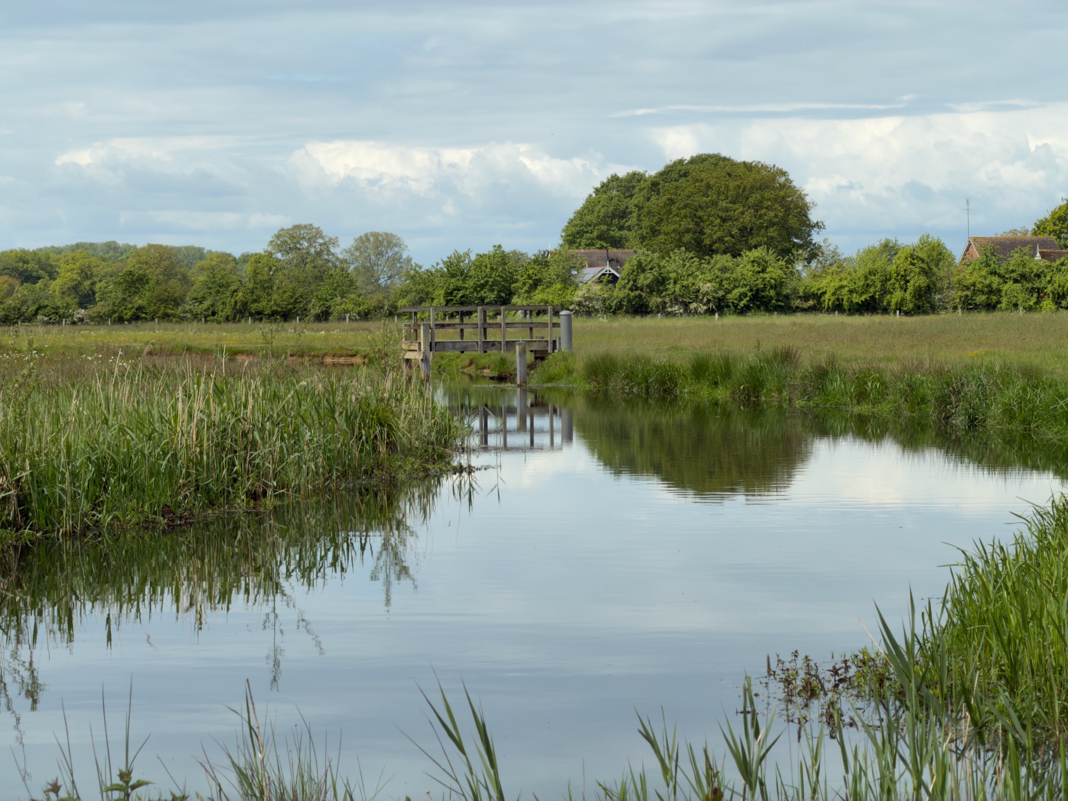 Small wooden viewing platform jutting into a wide bend of the Regge reflected in still water