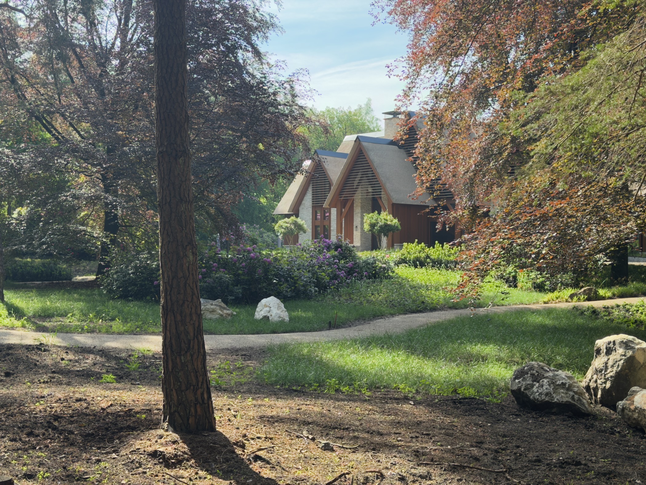 Wooden chalet-style house with flowering shrubs seen through the trees