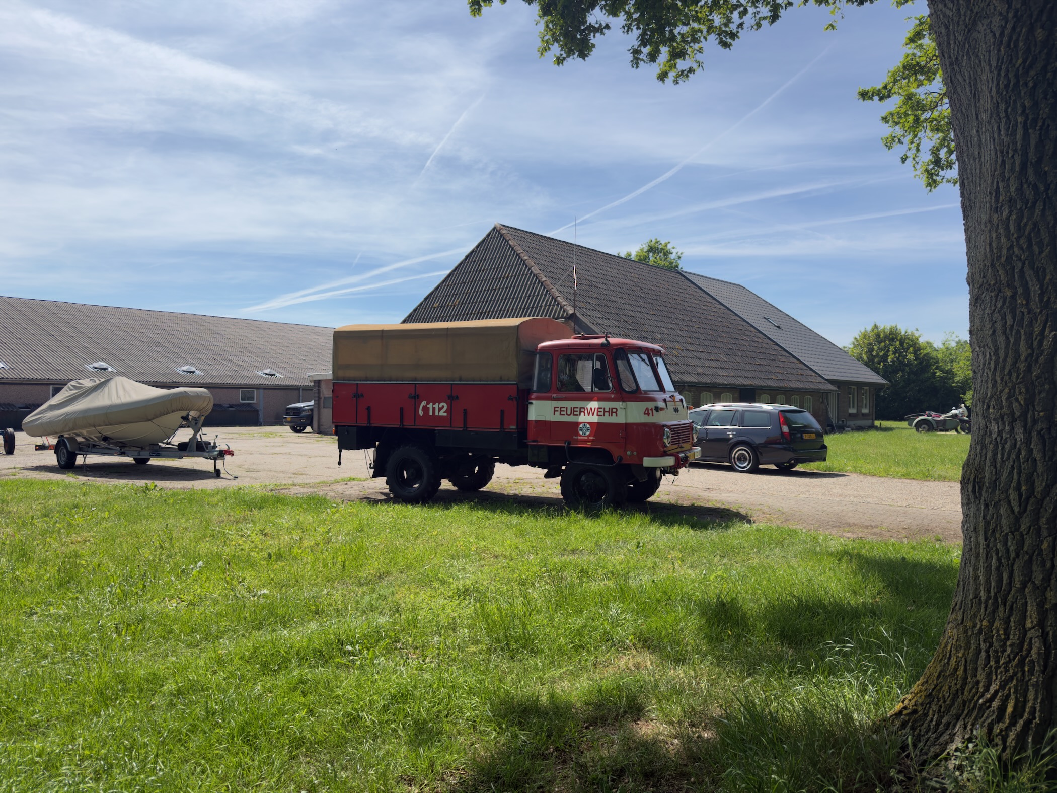 Vintage East German Feuerwehr fire truck and a boat parked in front of a barn