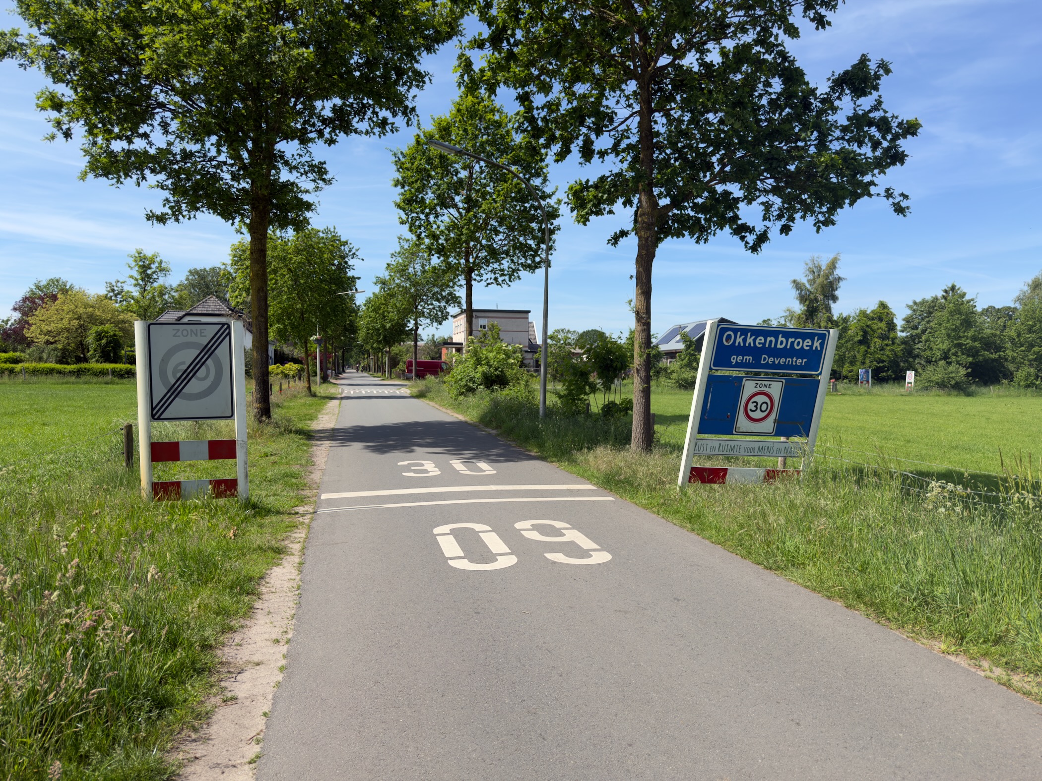 Approach to the village of Okkenbroek with a place-name sign and speed-limit markings on the road