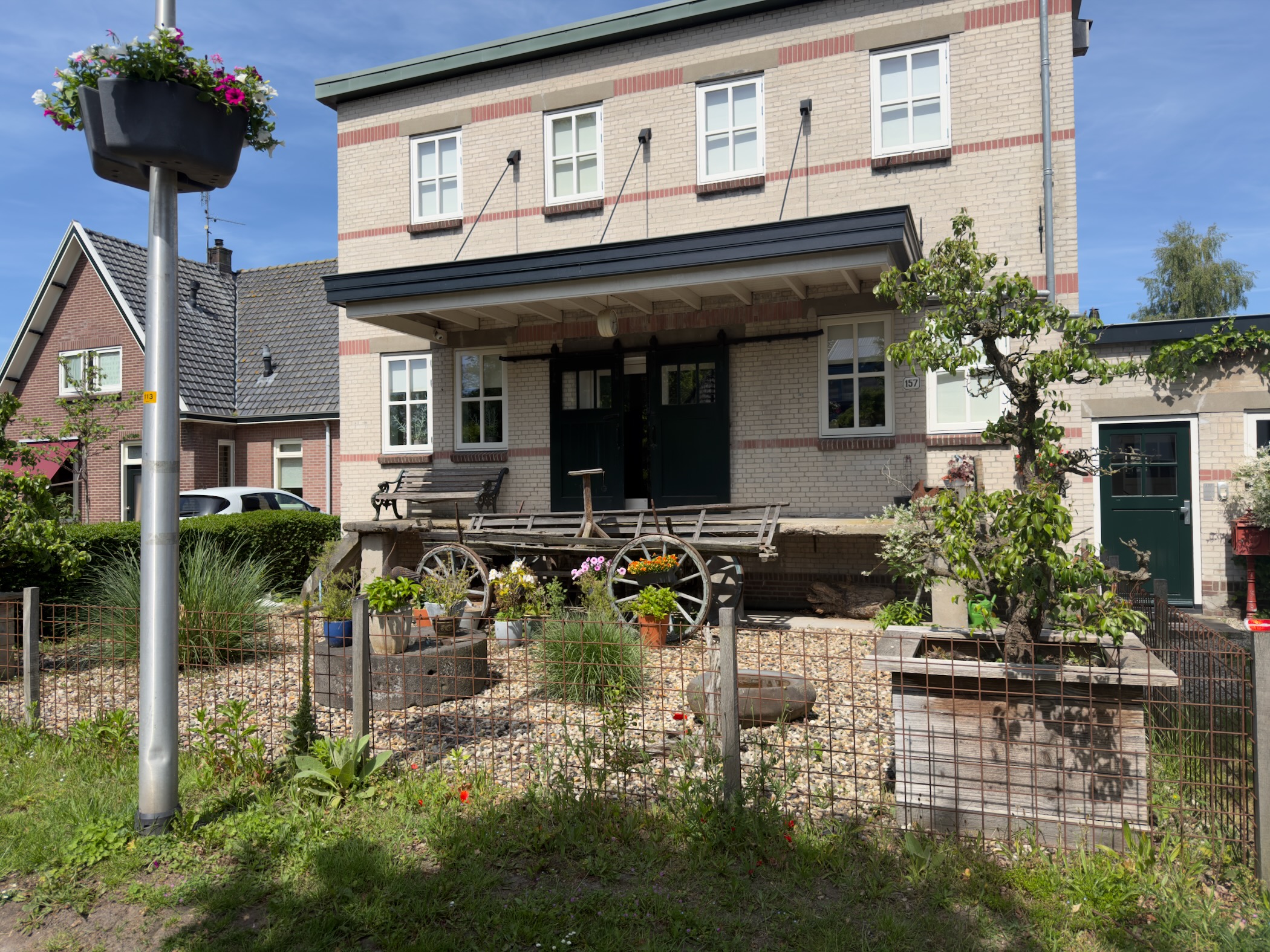 Brick village house with a covered porch and an old wagon parked in the front garden