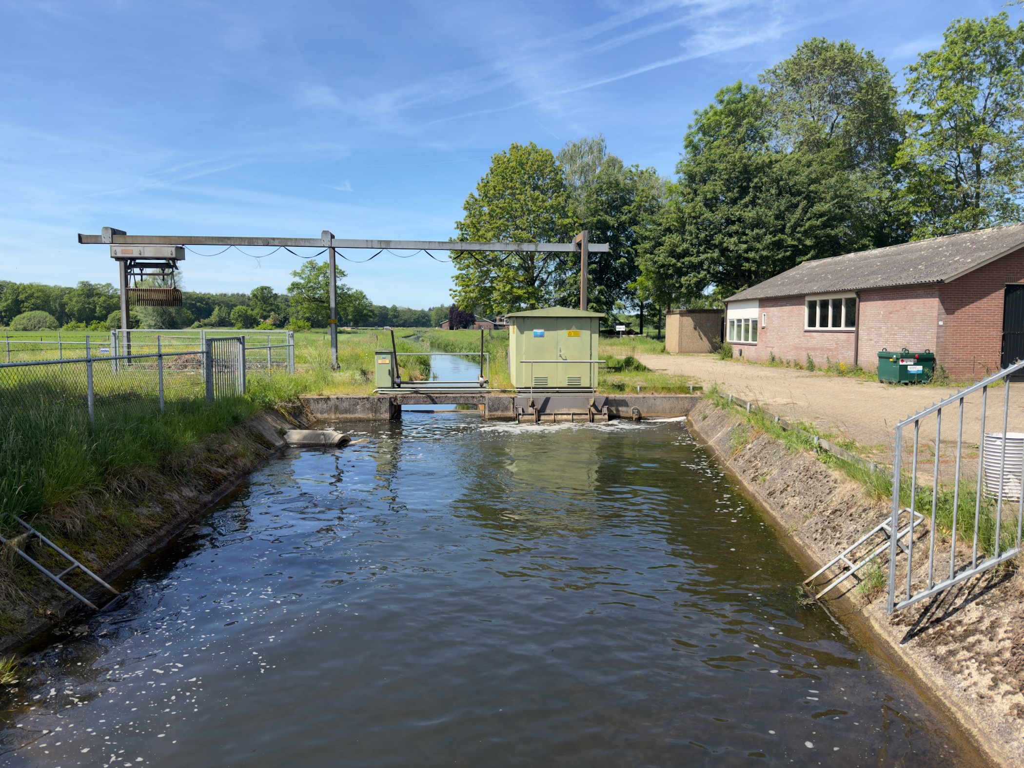 Concrete weir and sluice on a small canal beside a farm building