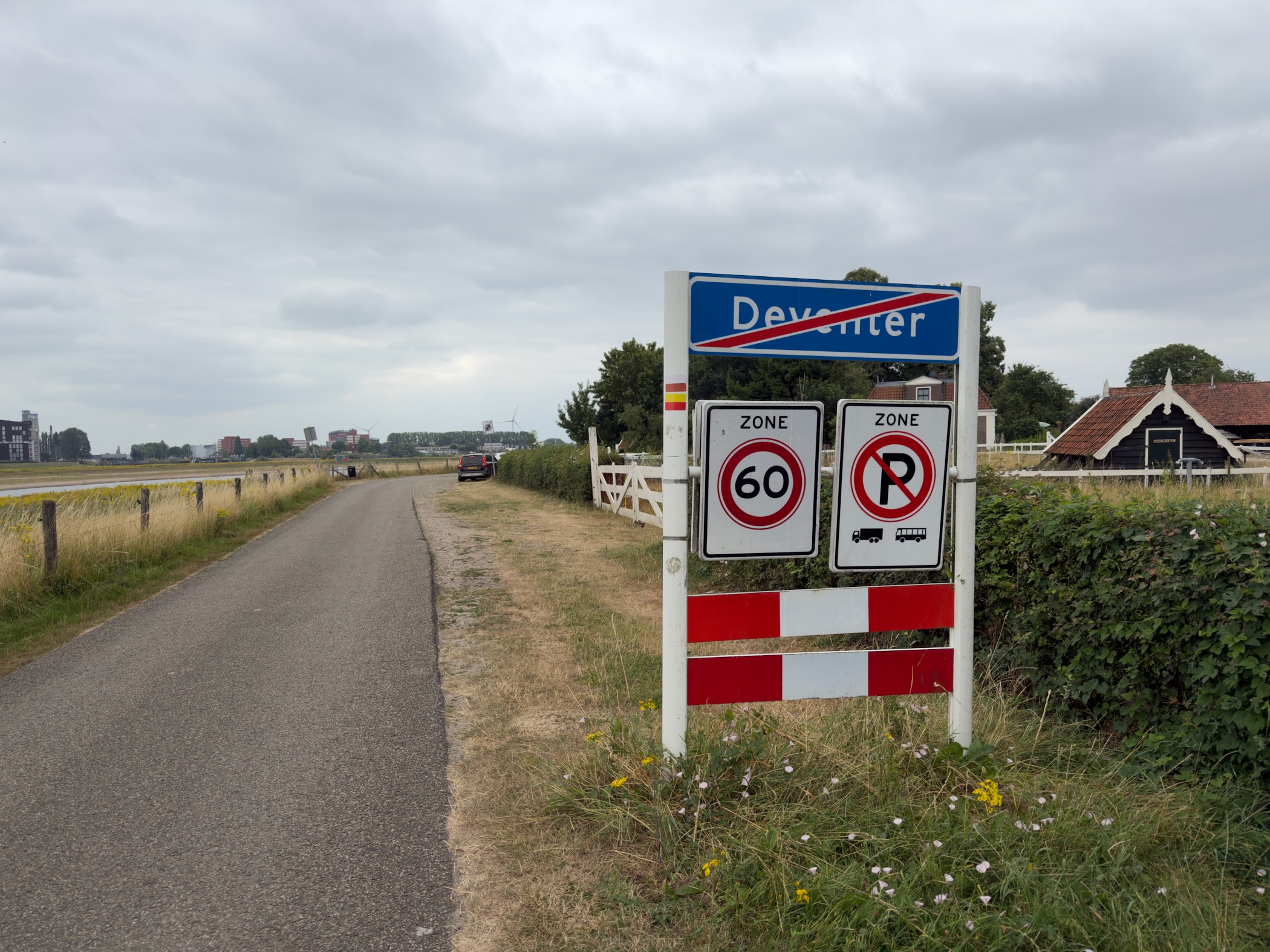 An end-of-Deventer place-name sign with 60 km/h and no-parking zone signs beside a rural road and fields.