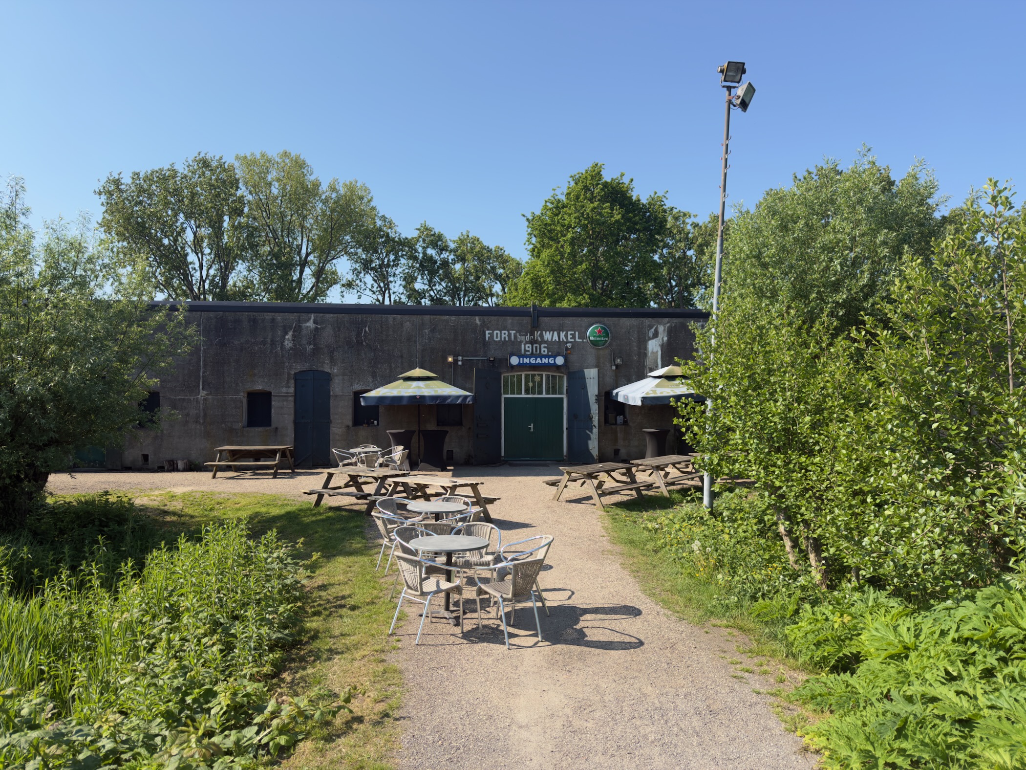 Fort de Kwakel, a low concrete bunker of the Defence Line of Amsterdam, with picnic tables and umbrellas in front