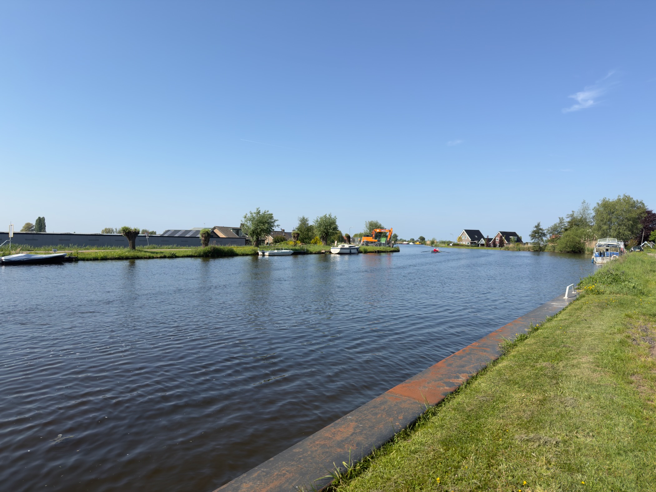 Wide view of the Amstel river with moored boats and houses along the far bank