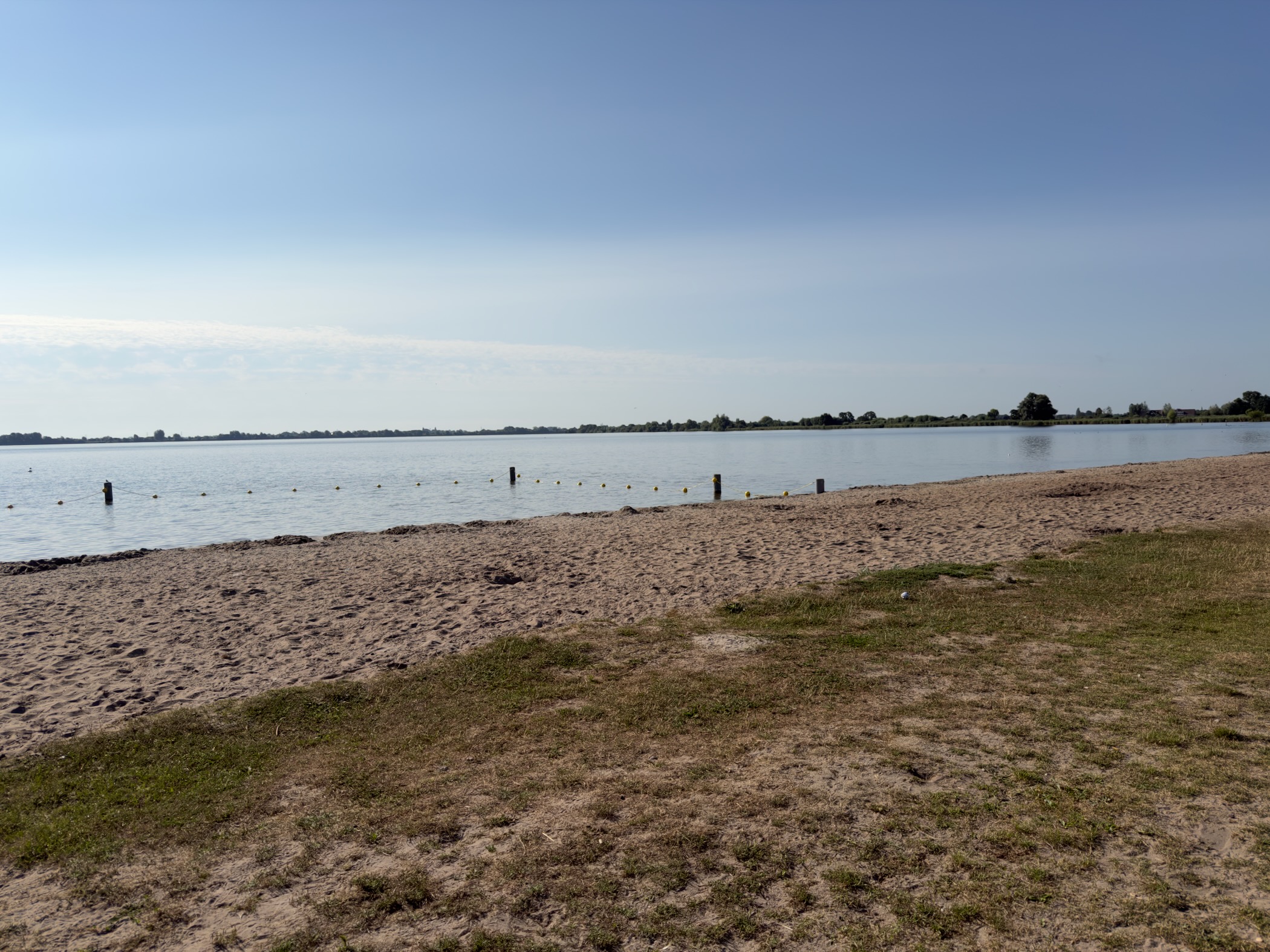 Sandy swimming beach on the Reeuwijkse Plassen with a line of yellow buoy markers stretching into open water