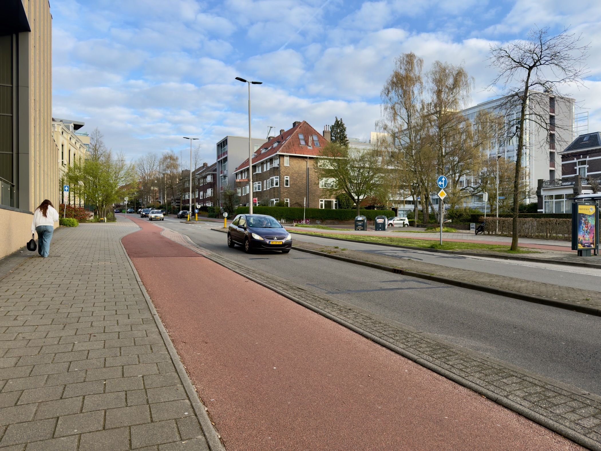 Street in Arnhem with a red bicycle lane and cars passing by