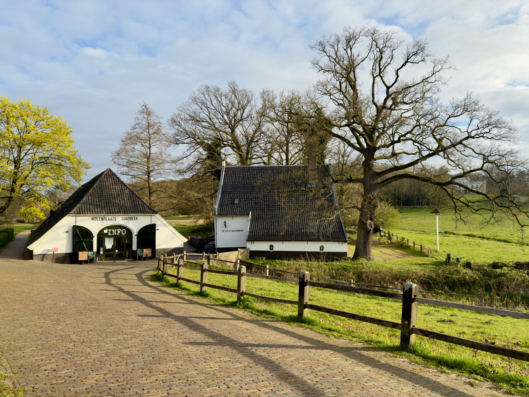 Traditional farmstead with an info sign and green pastures at Sonsbeek