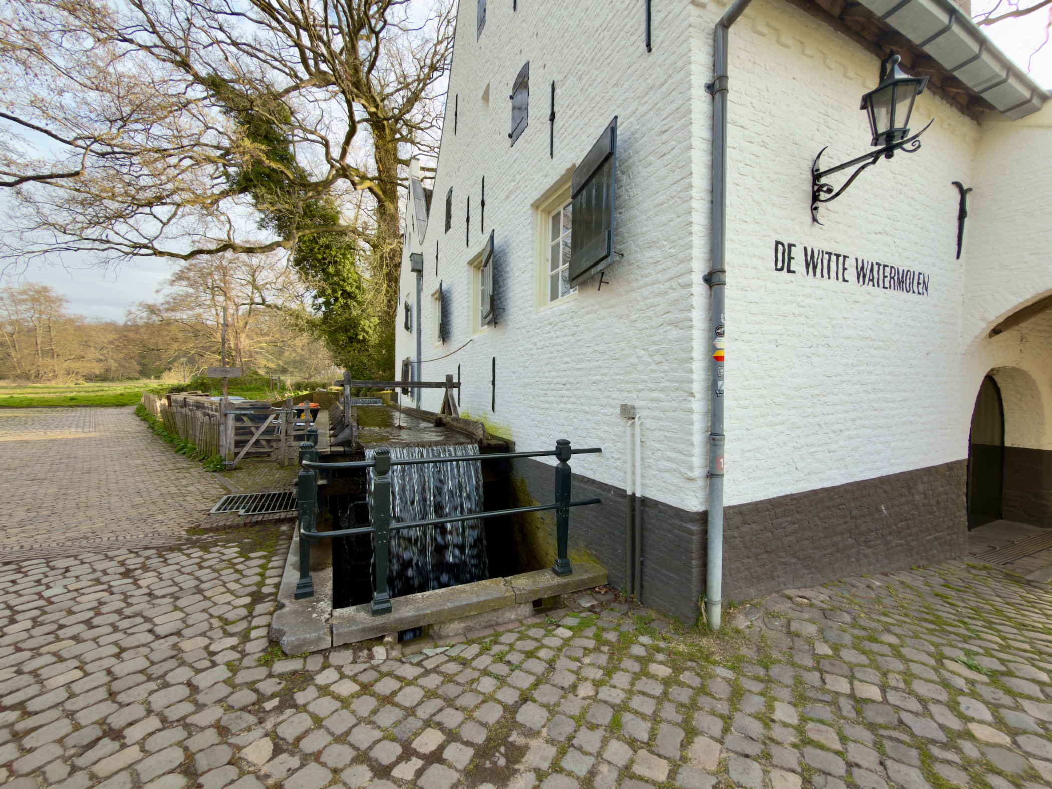 De Witte Watermolen, a white watermill with water flowing through the sluice