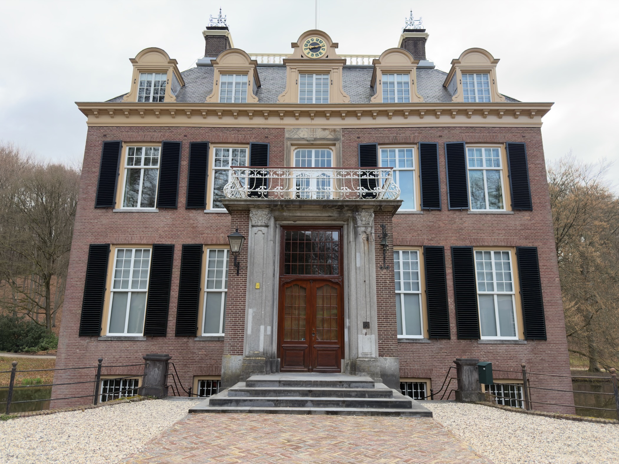 Front facade of a stately manor house with black shutters and a columned entrance