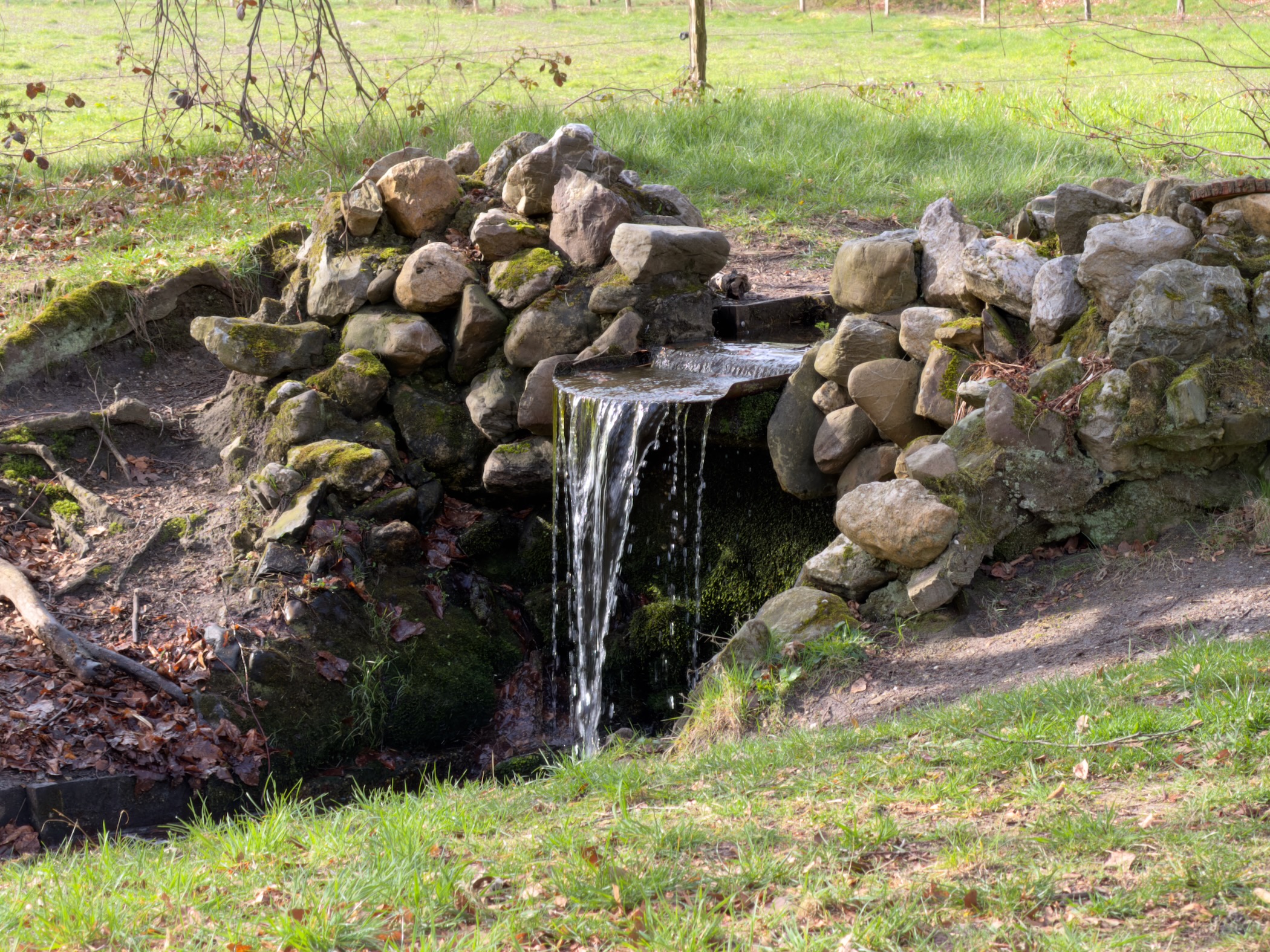 Small stone waterfall in a green meadow