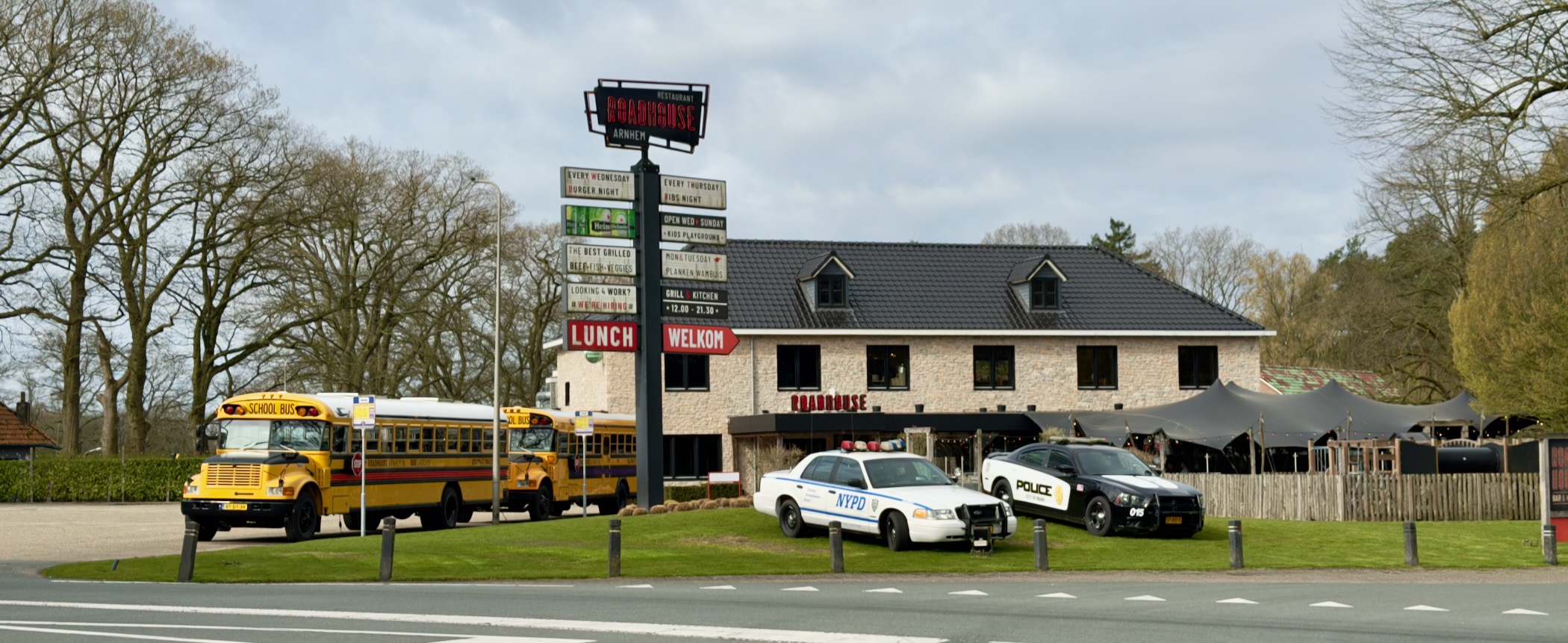 American-themed roadhouse restaurant with a yellow school bus and police car parked outside