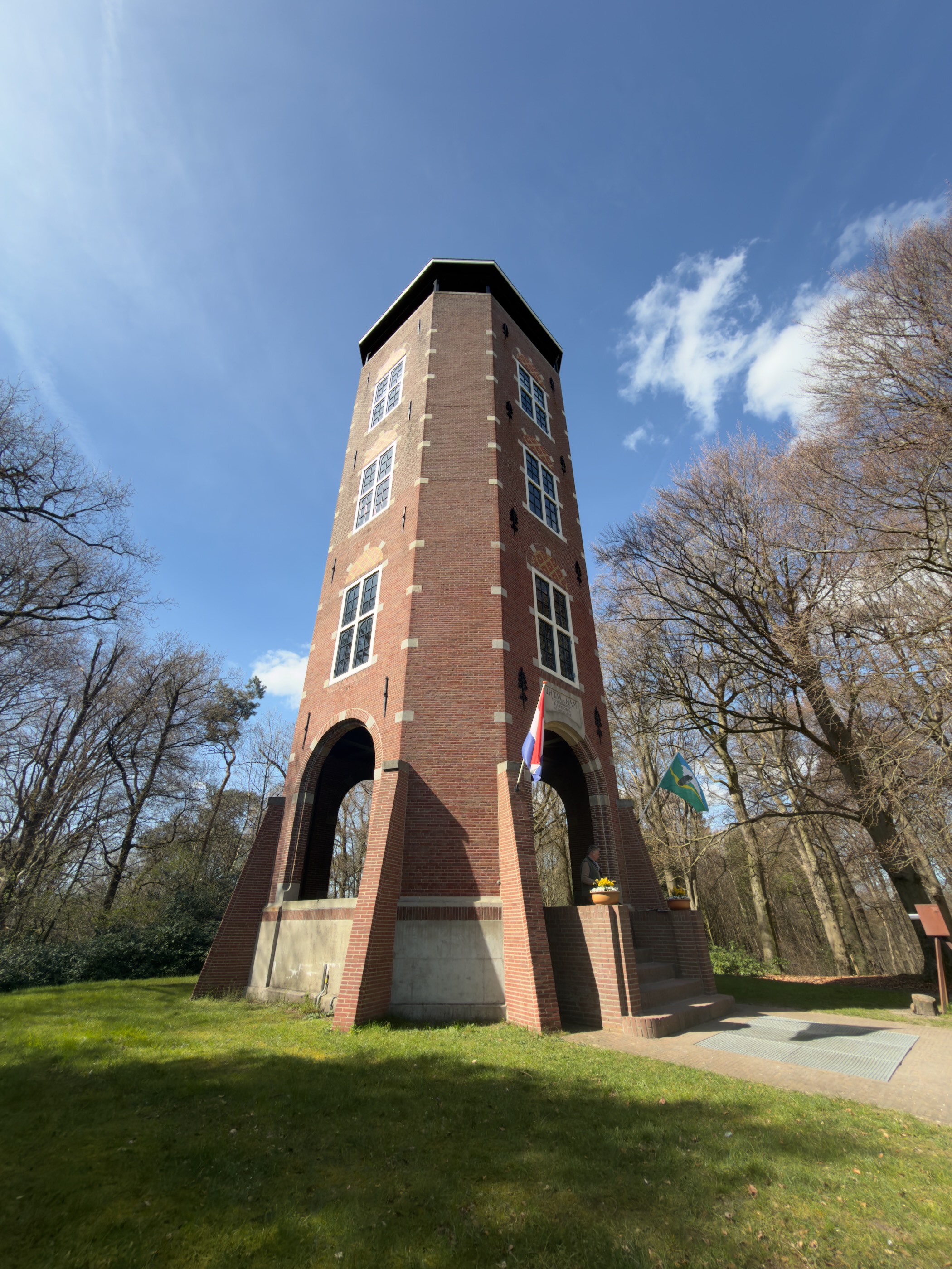 Brick observation tower with a Dutch flag surrounded by bare trees