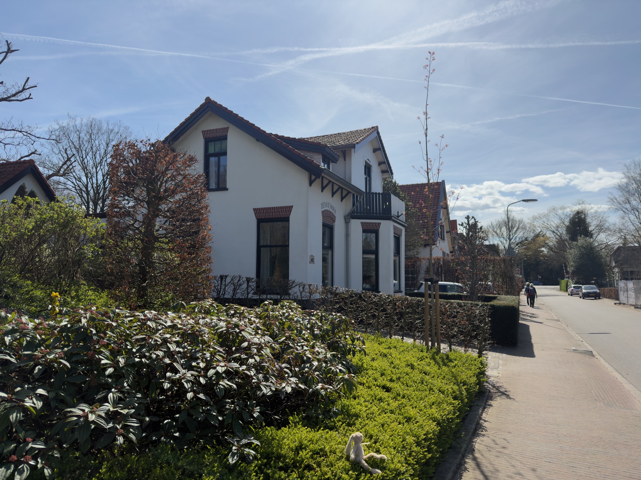 White villa with hedges and gardens along a village street in Lunteren
