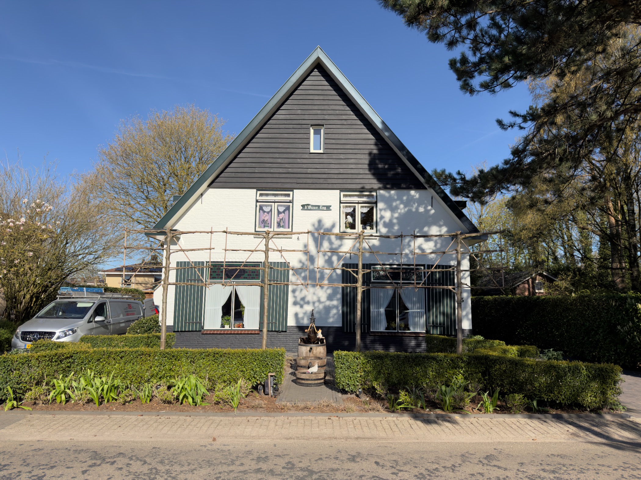 White Dutch farmhouse with black gable and scaffolding under renovation