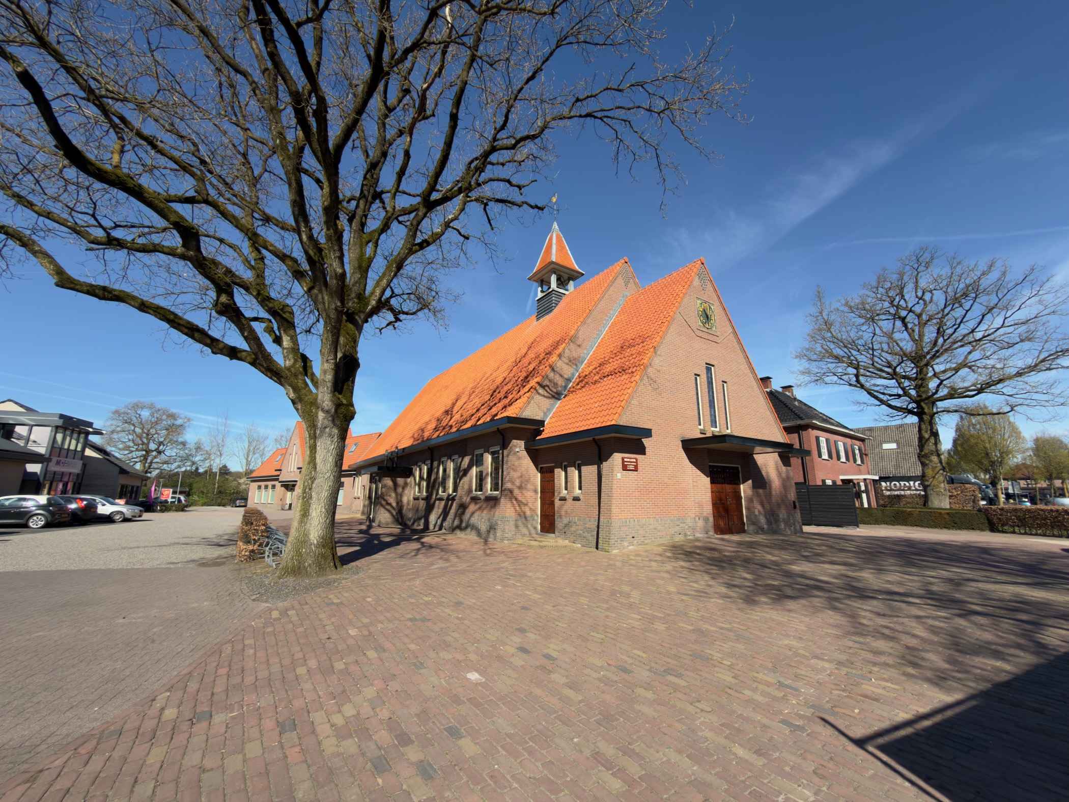 Brick church with an orange roof and small bell tower in Harskamp