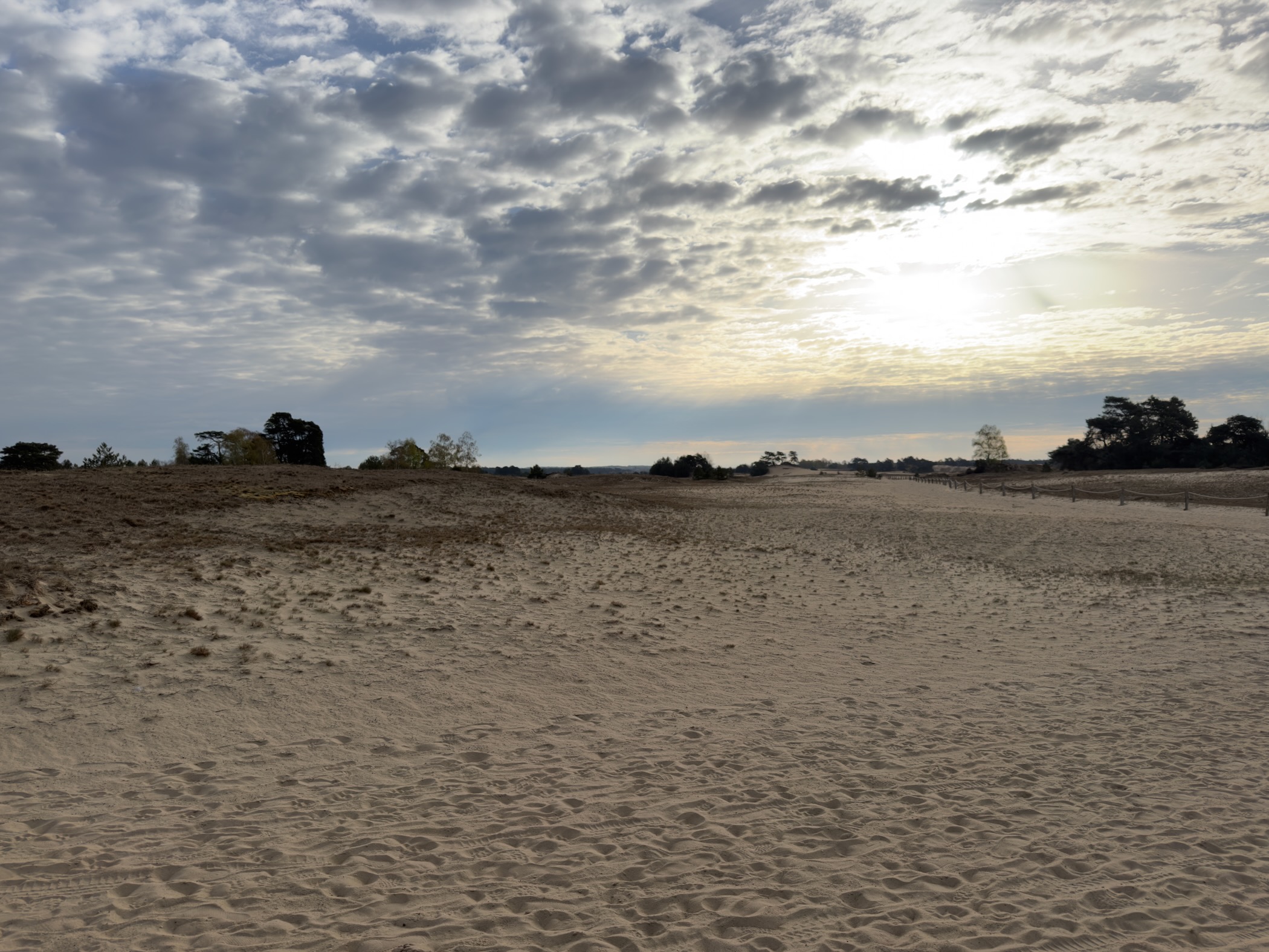 Vast sandy landscape of Kootwijkerzand with sun breaking through clouds