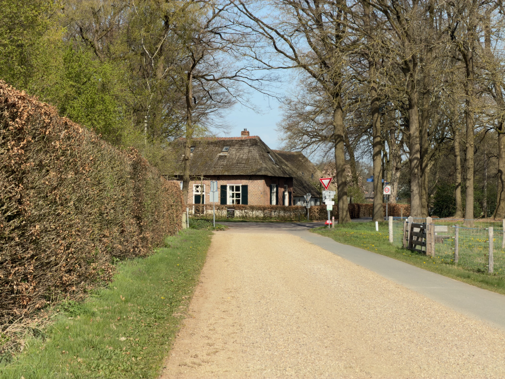 Sandy lane approaching a thatched-roof farmhouse near Garderen