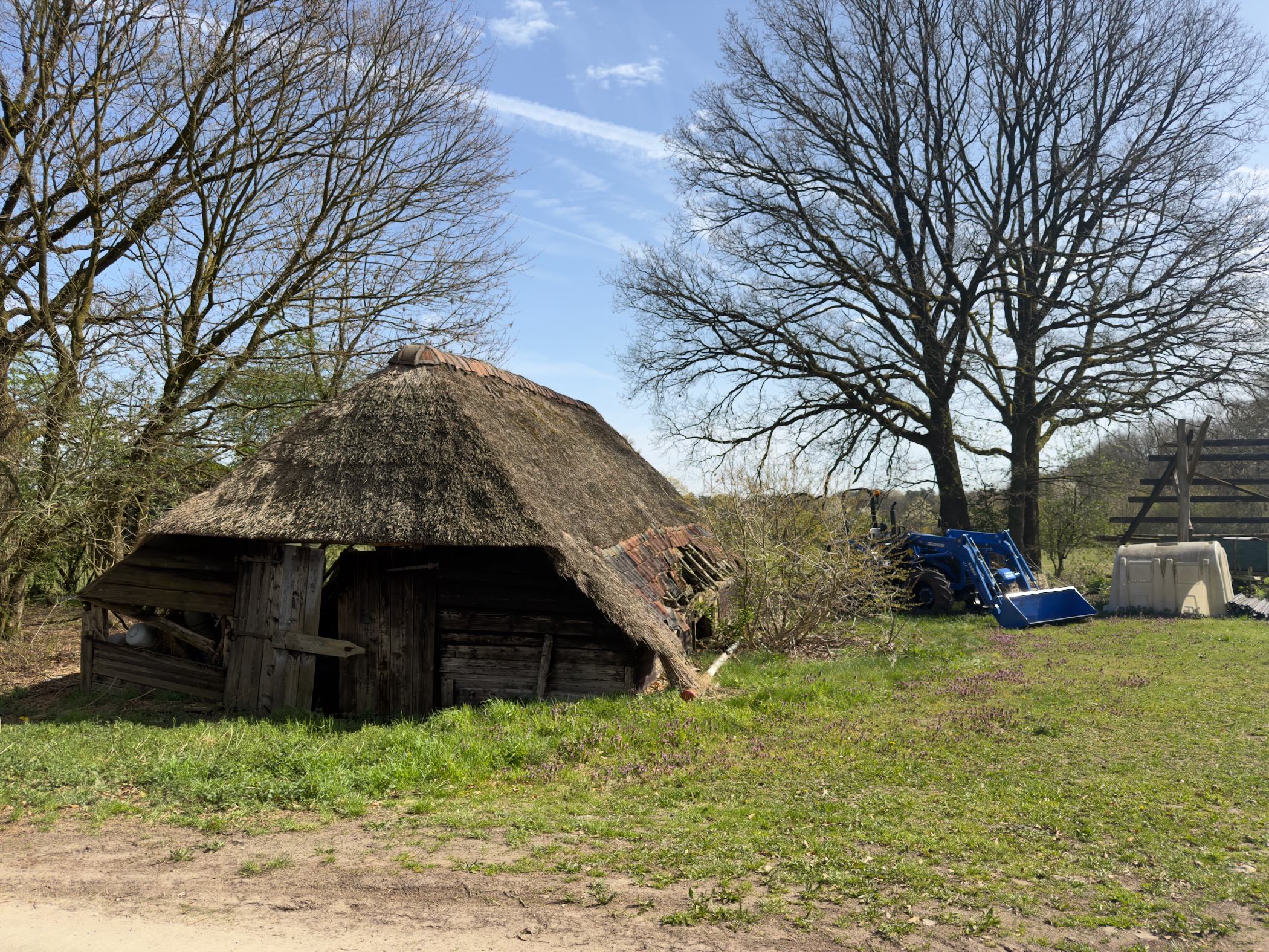 Old thatched barn with weathered wooden walls in a grassy yard