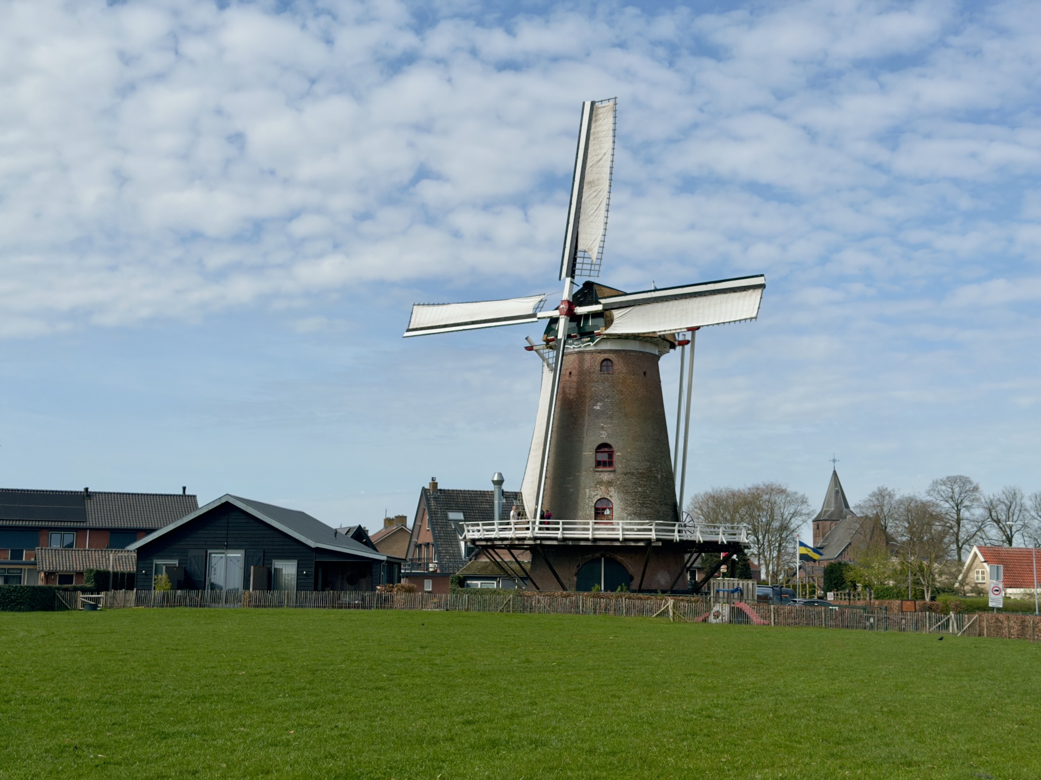 Windmill of Garderen rising above houses and a church spire