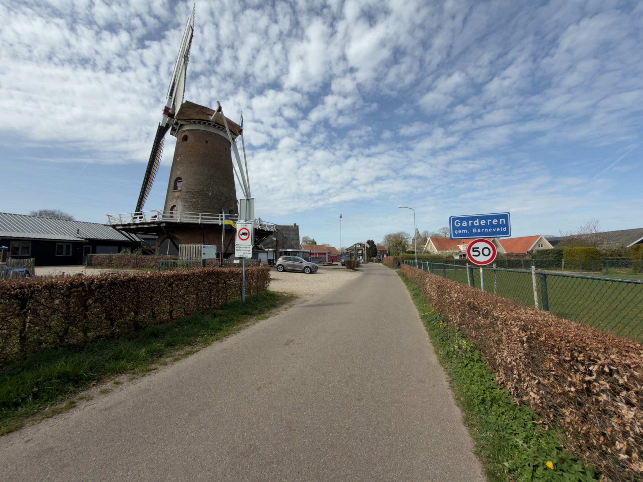 Garderen village sign beside the windmill and a beech hedge