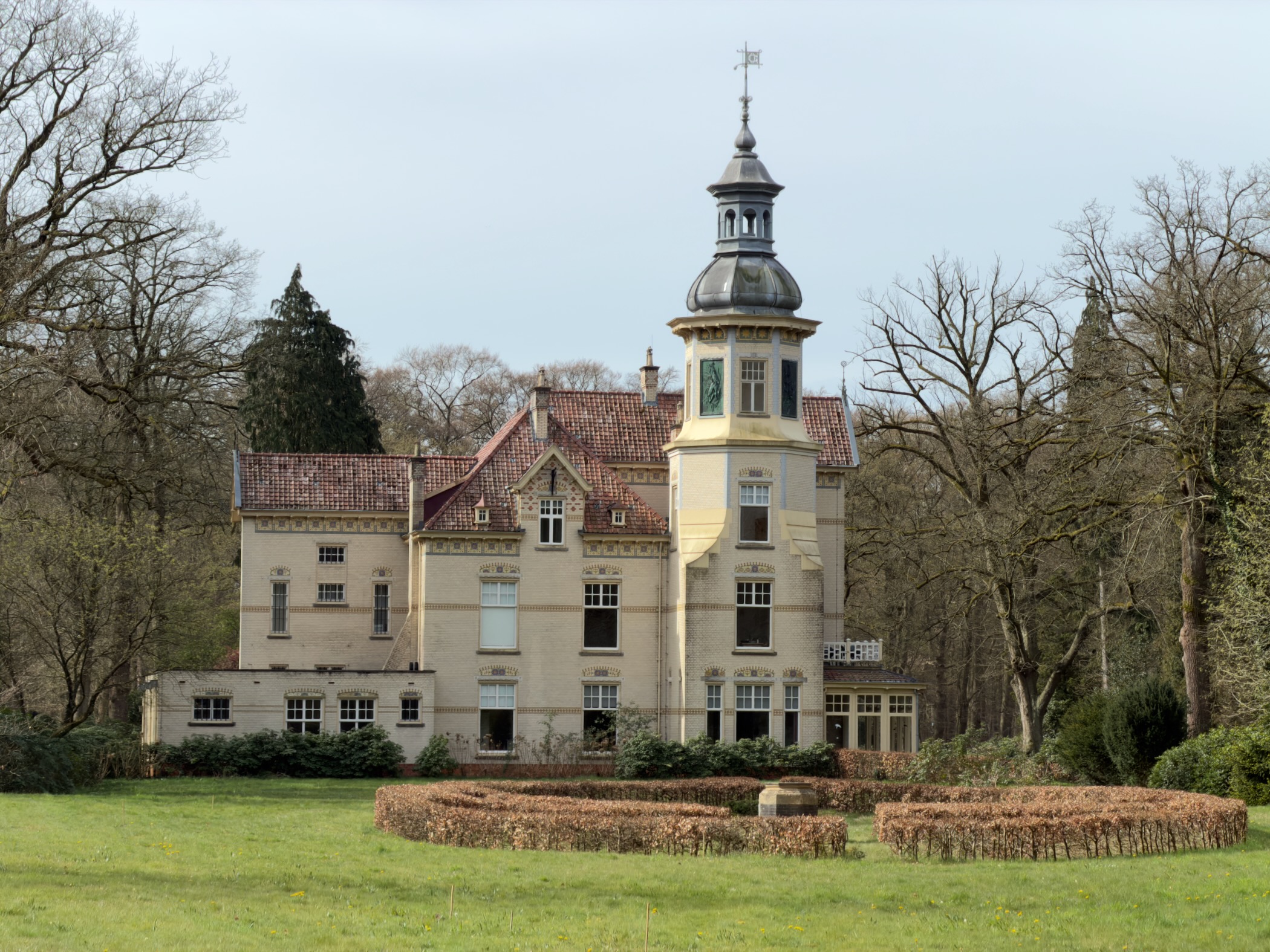 Stately manor house with a yellow tower surrounded by a manicured lawn