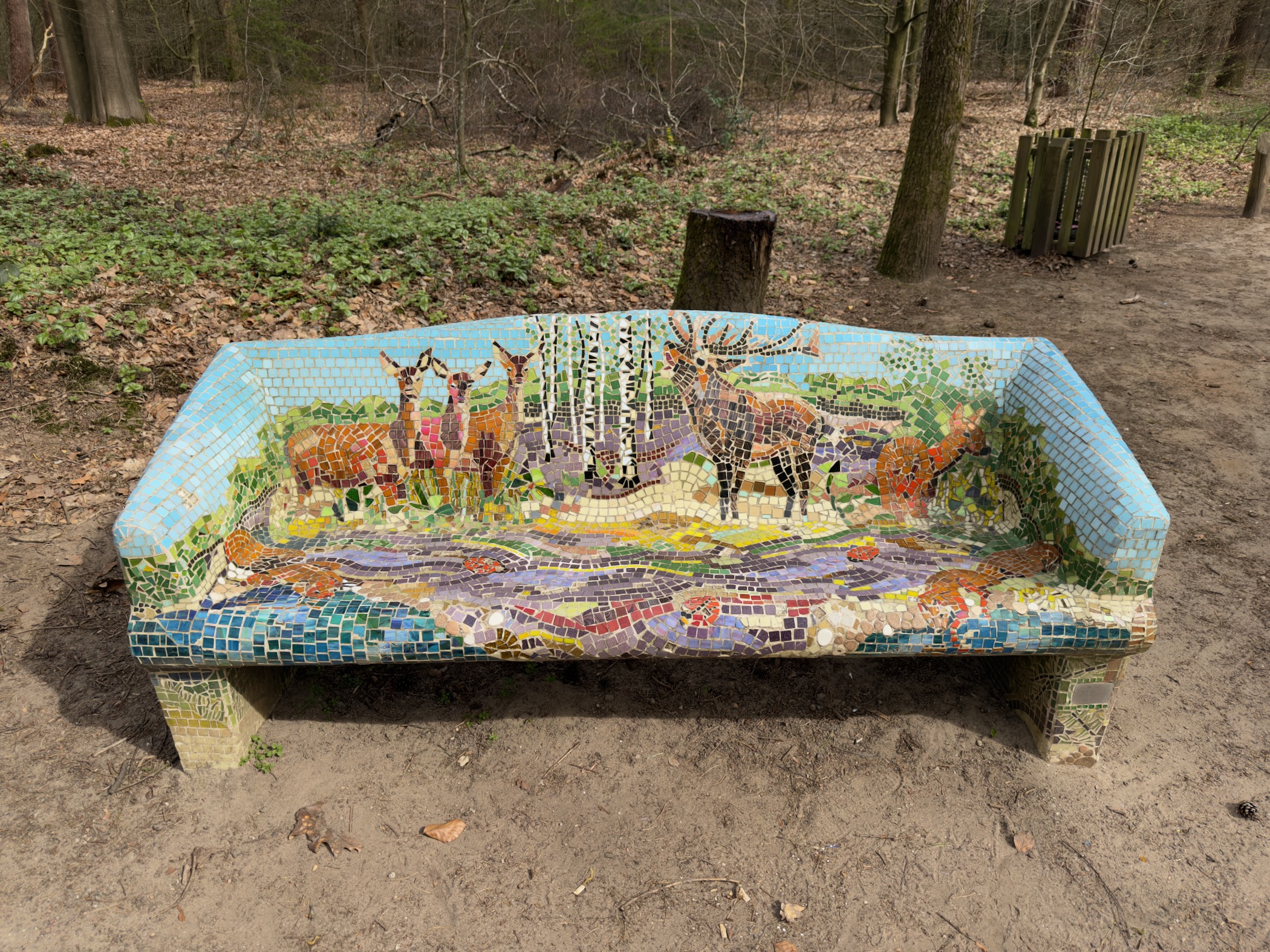 Colourful mosaic bench depicting deer and heathland in a forest clearing