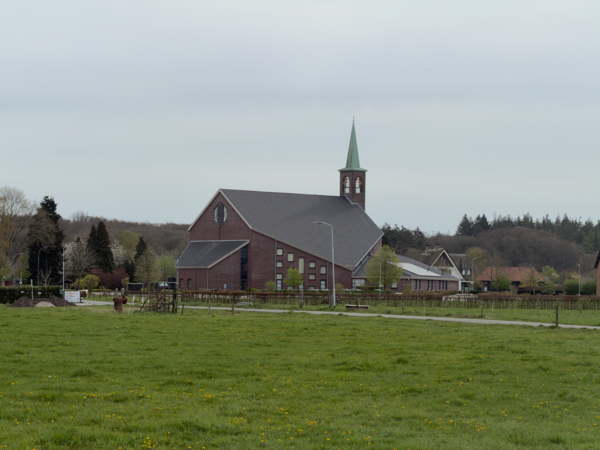 Brick church with green spire viewed across green pastures near Elspeet