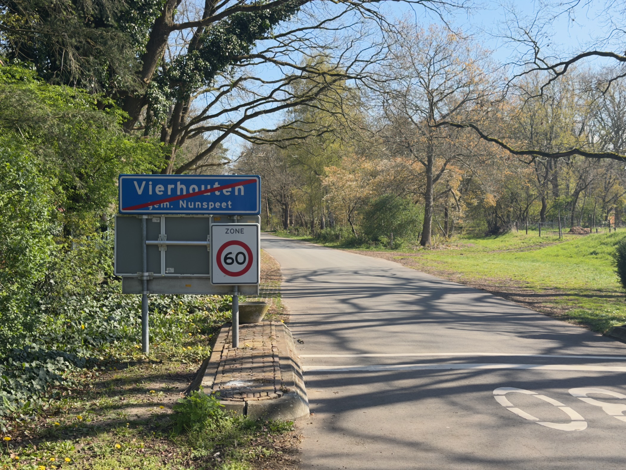 Blue place-name sign for Vierhouten with a 60 km/h speed limit along a tree-lined road