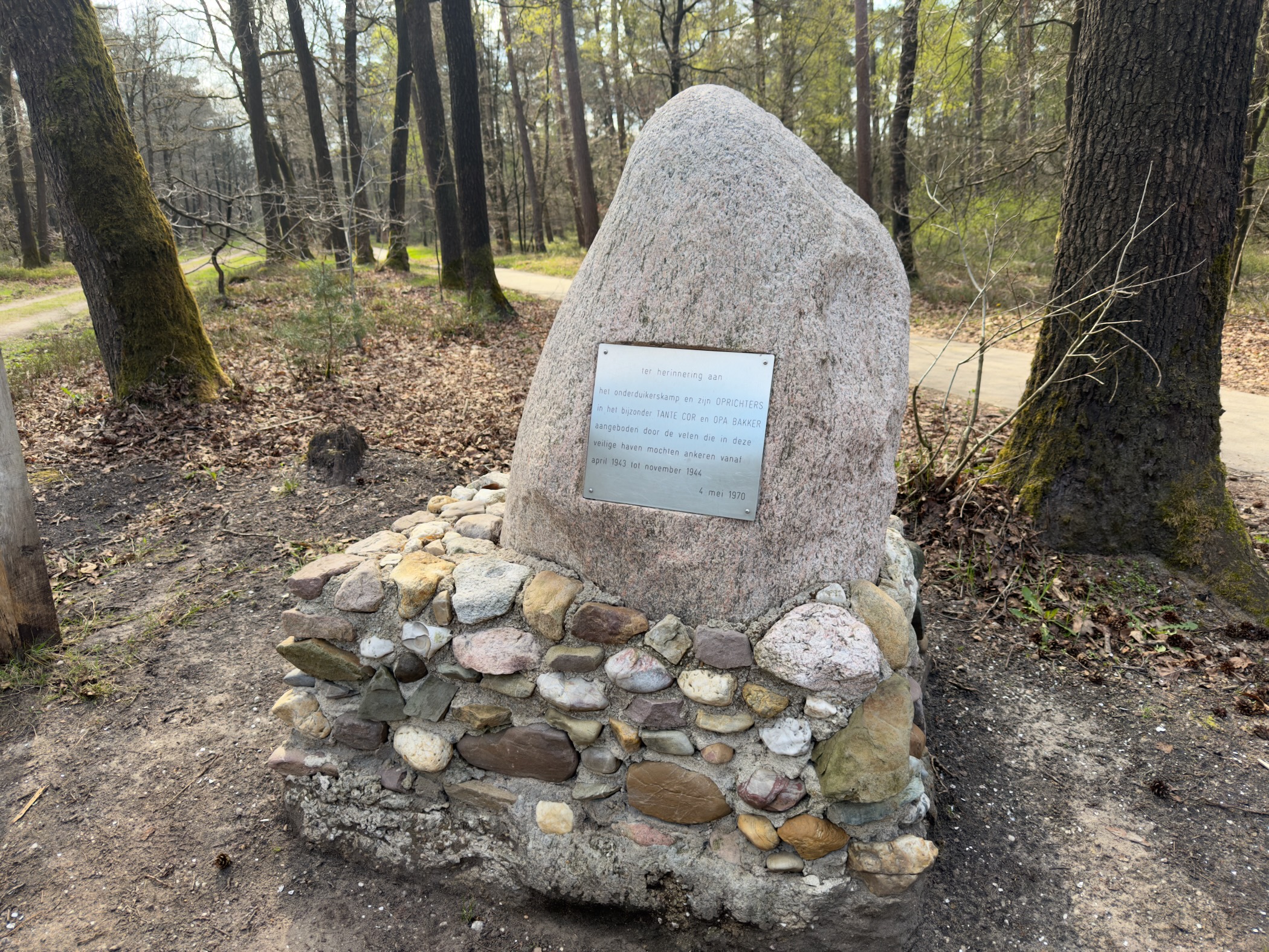 Memorial stone with a commemorative plaque on a cobblestone base in the woods