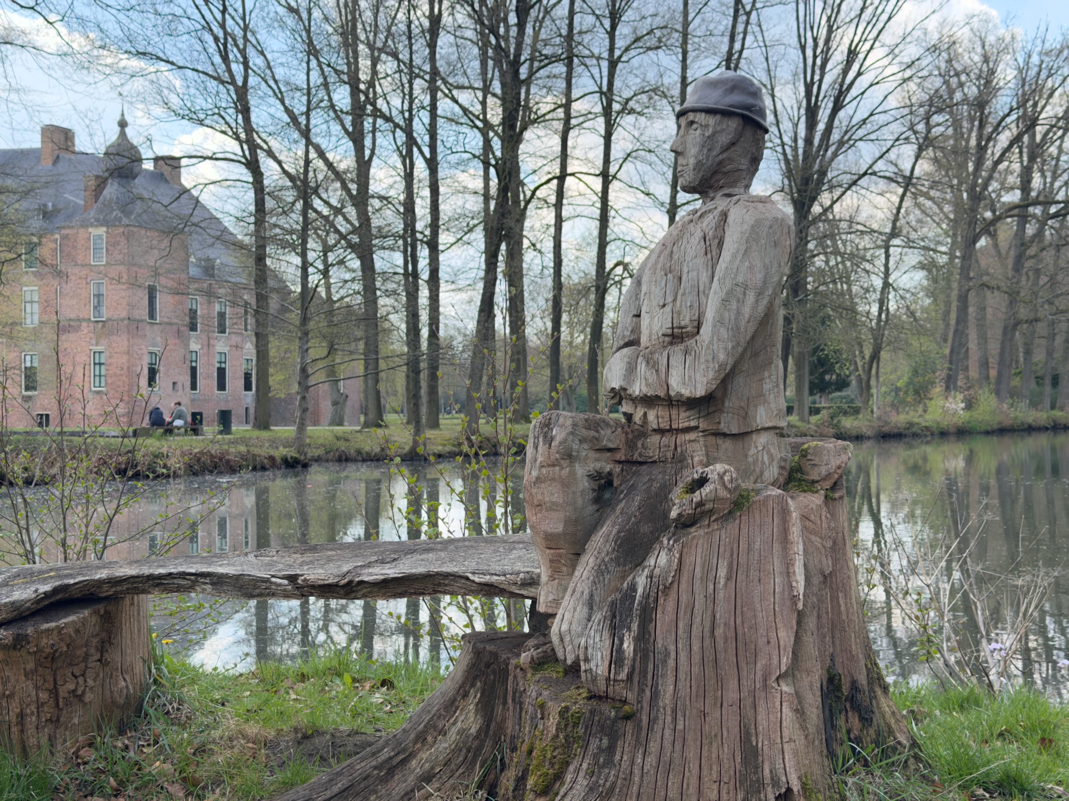 Carved wooden soldier figure on a tree stump with a castle reflected in the moat behind
