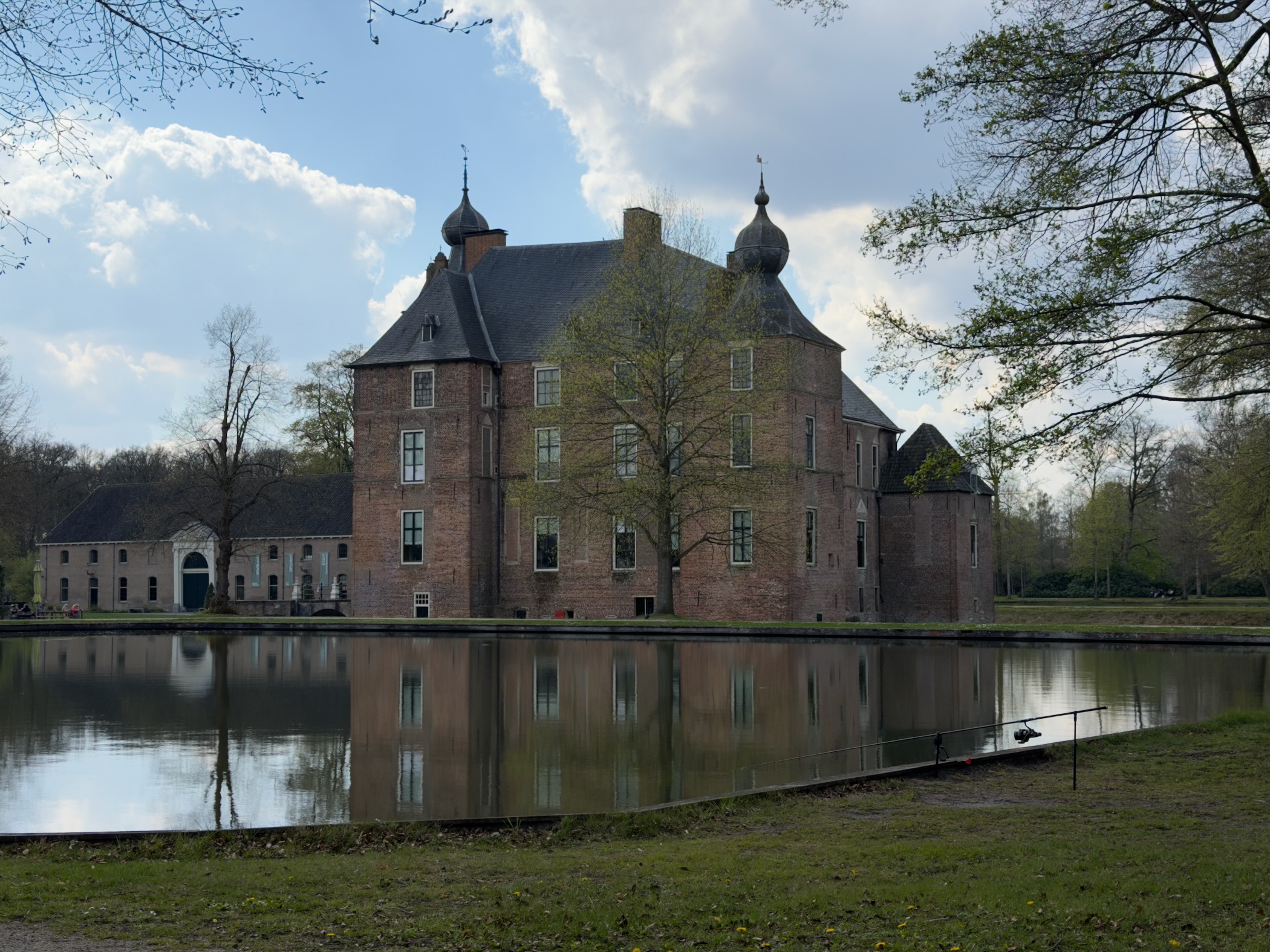 Brick castle with onion-domed towers reflected in a wide moat under a cloudy sky