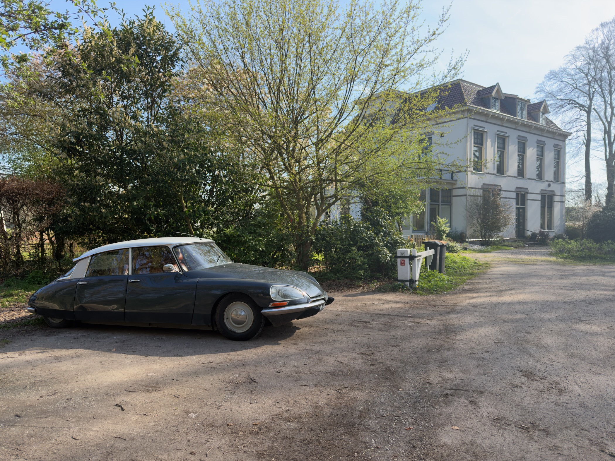 Classic Citro\u00ebn DS parked in front of a white manor house