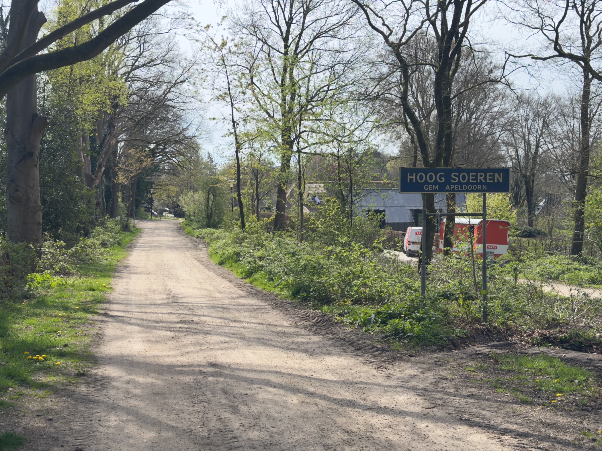 Unpaved road leading into Hoog Soeren with the blue village name sign