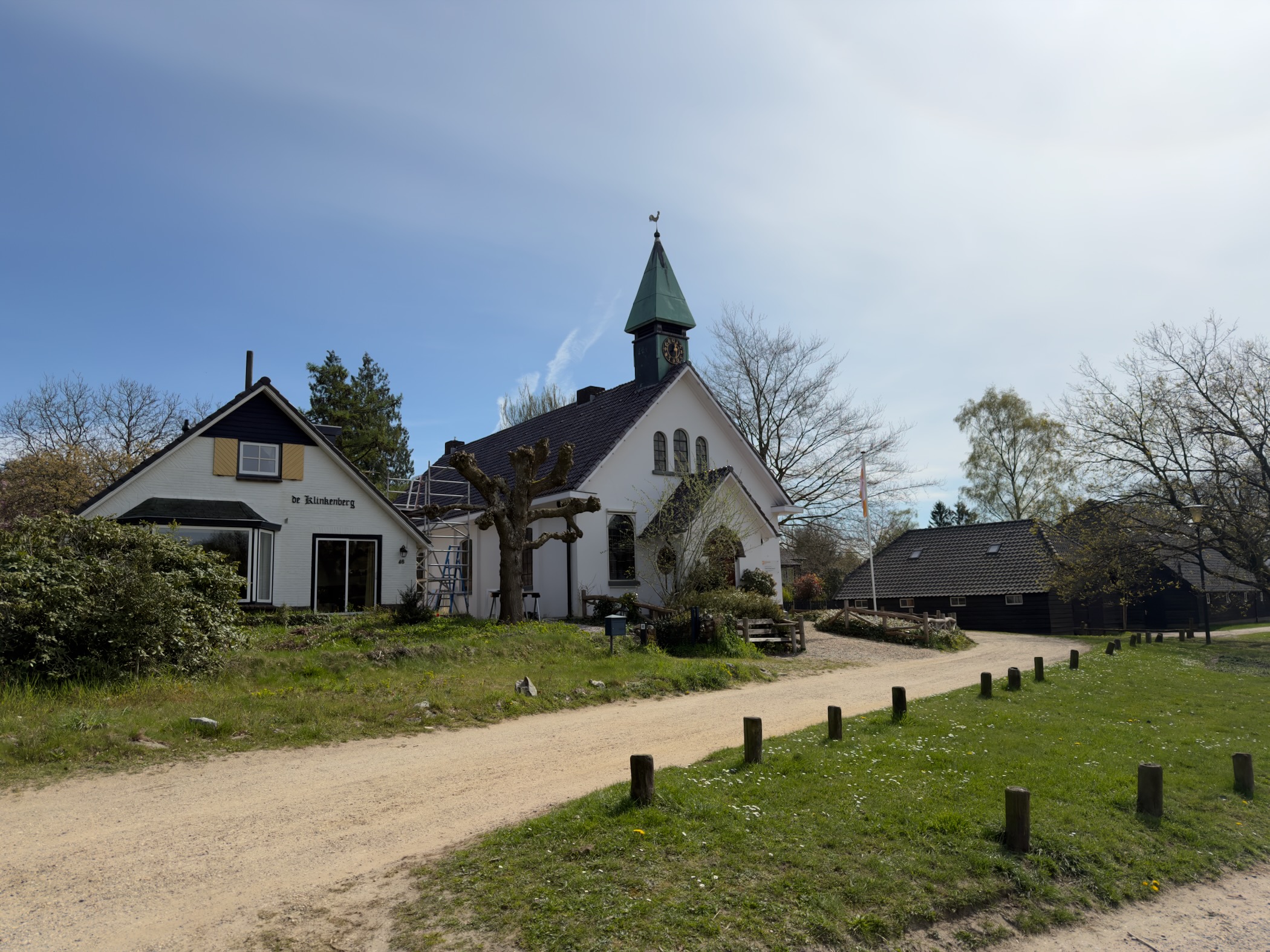 White church with a green spire in Hoog Soeren village along a sandy path