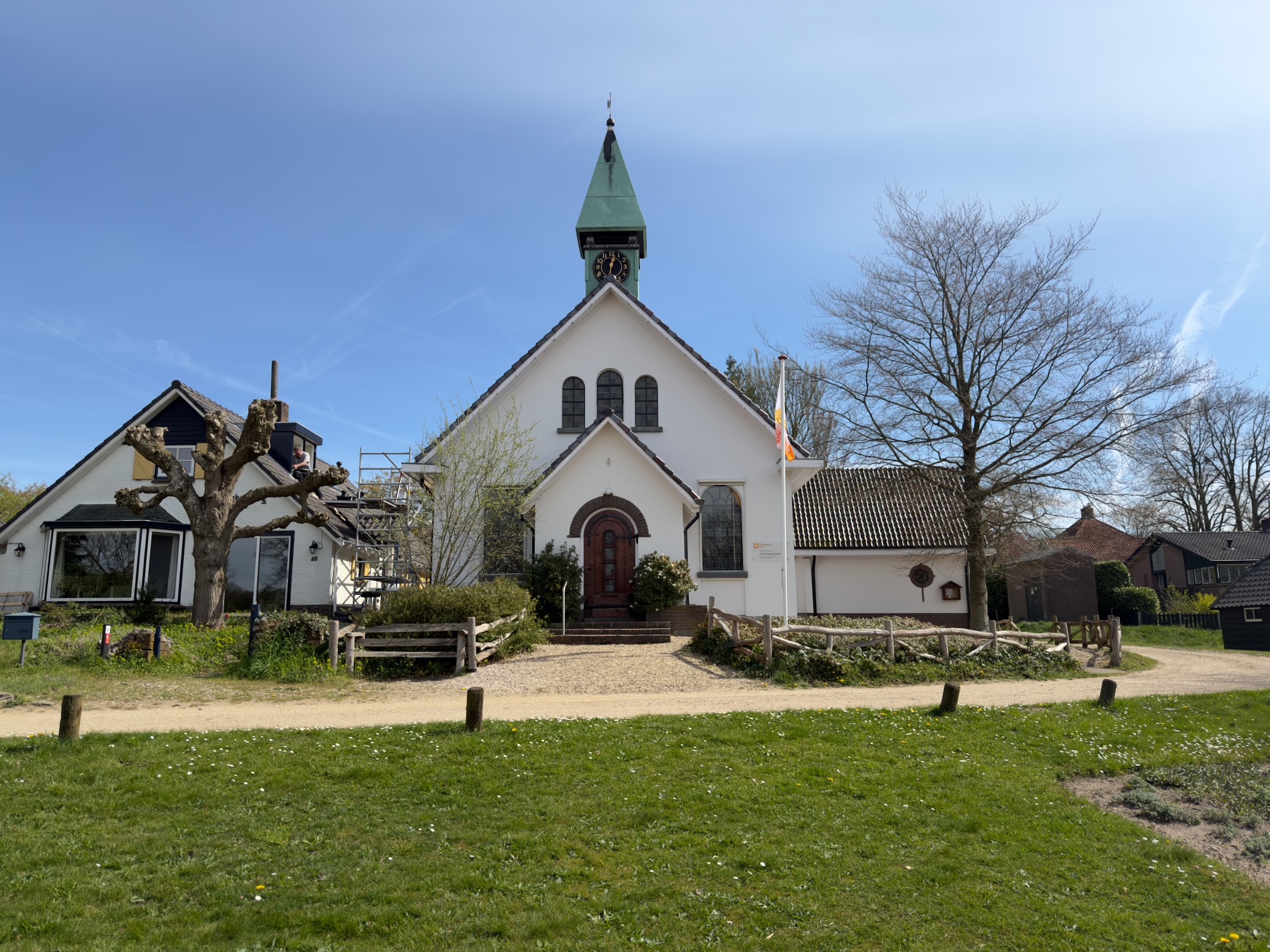 Front view of the white church in Hoog Soeren with its arched entrance and green spire