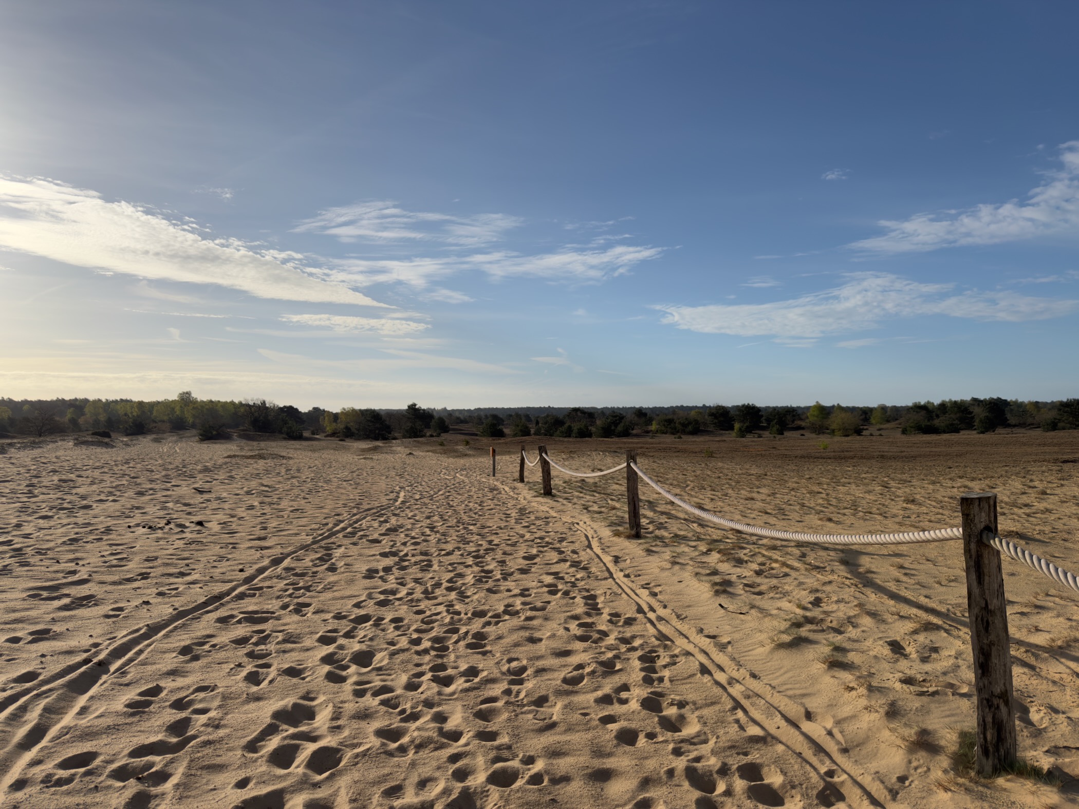 Rope fence marking the path across the sand drift with footprints in the sand