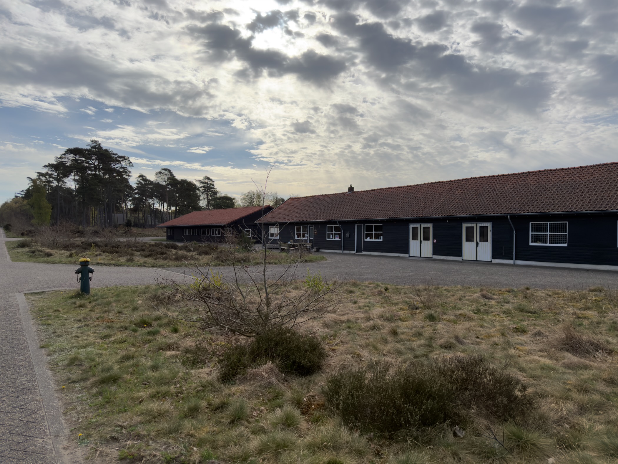 Dark wooden utility buildings on the Radio Kootwijk grounds under a cloudy sky