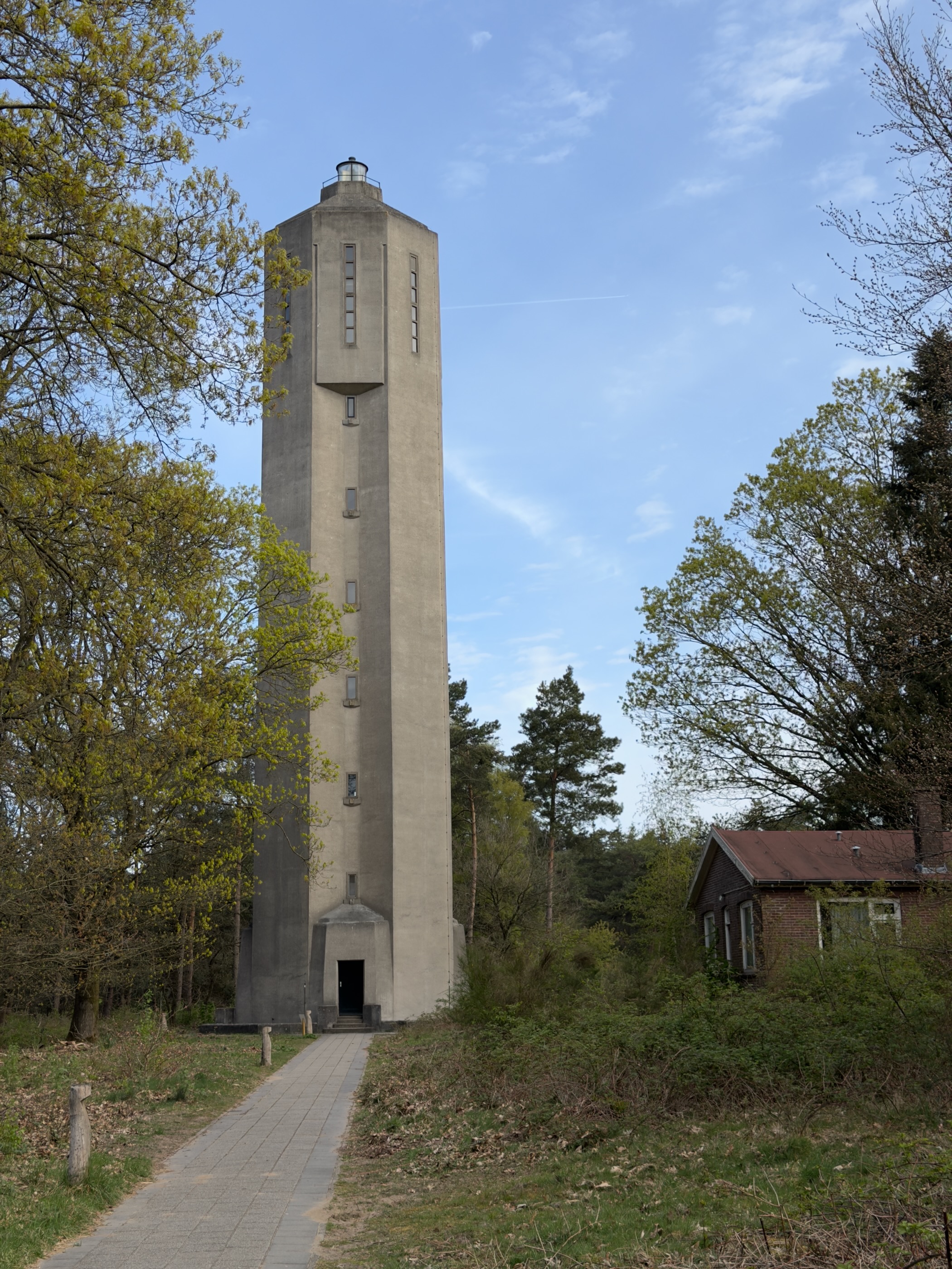 Tall concrete water tower at Radio Kootwijk with a small brick building beside it