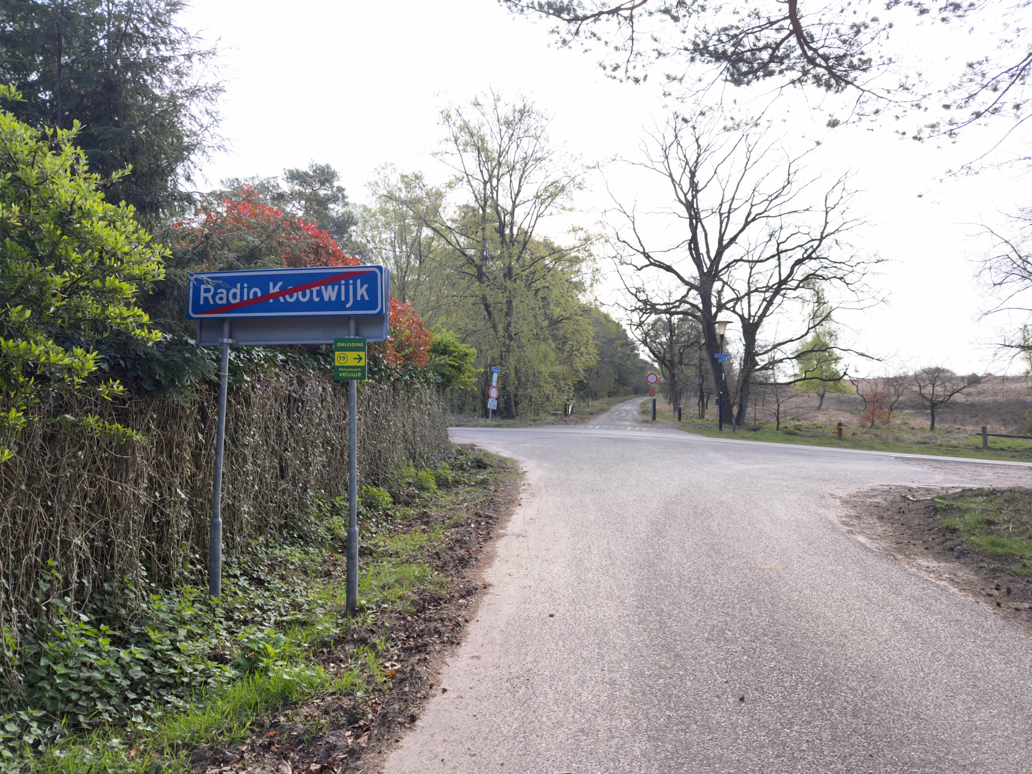 Road sign marking the exit of Radio Kootwijk village with a road leading into heathland