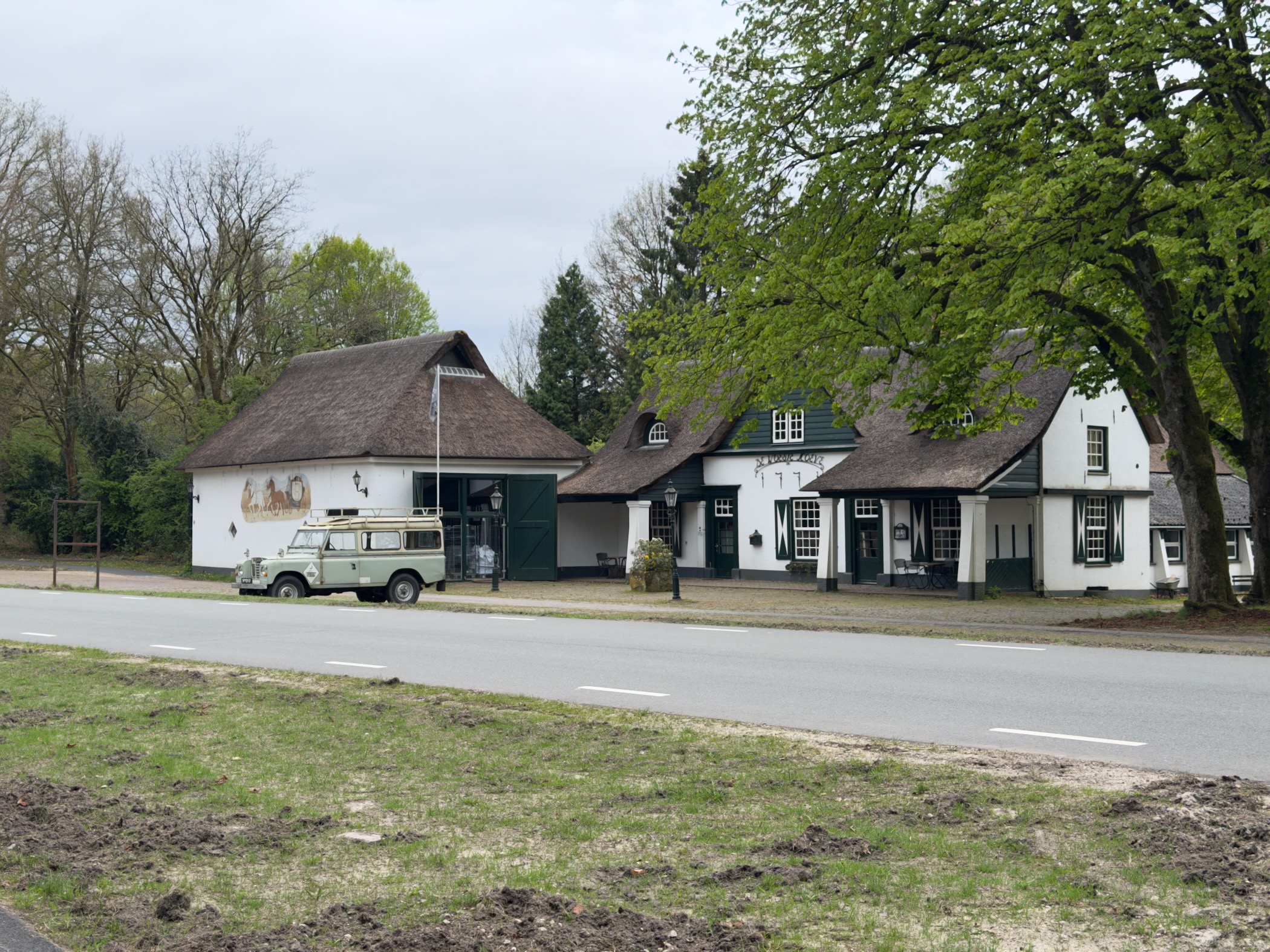 Thatched-roof inn at Woeste Hoeve with a vintage Land Rover parked in front