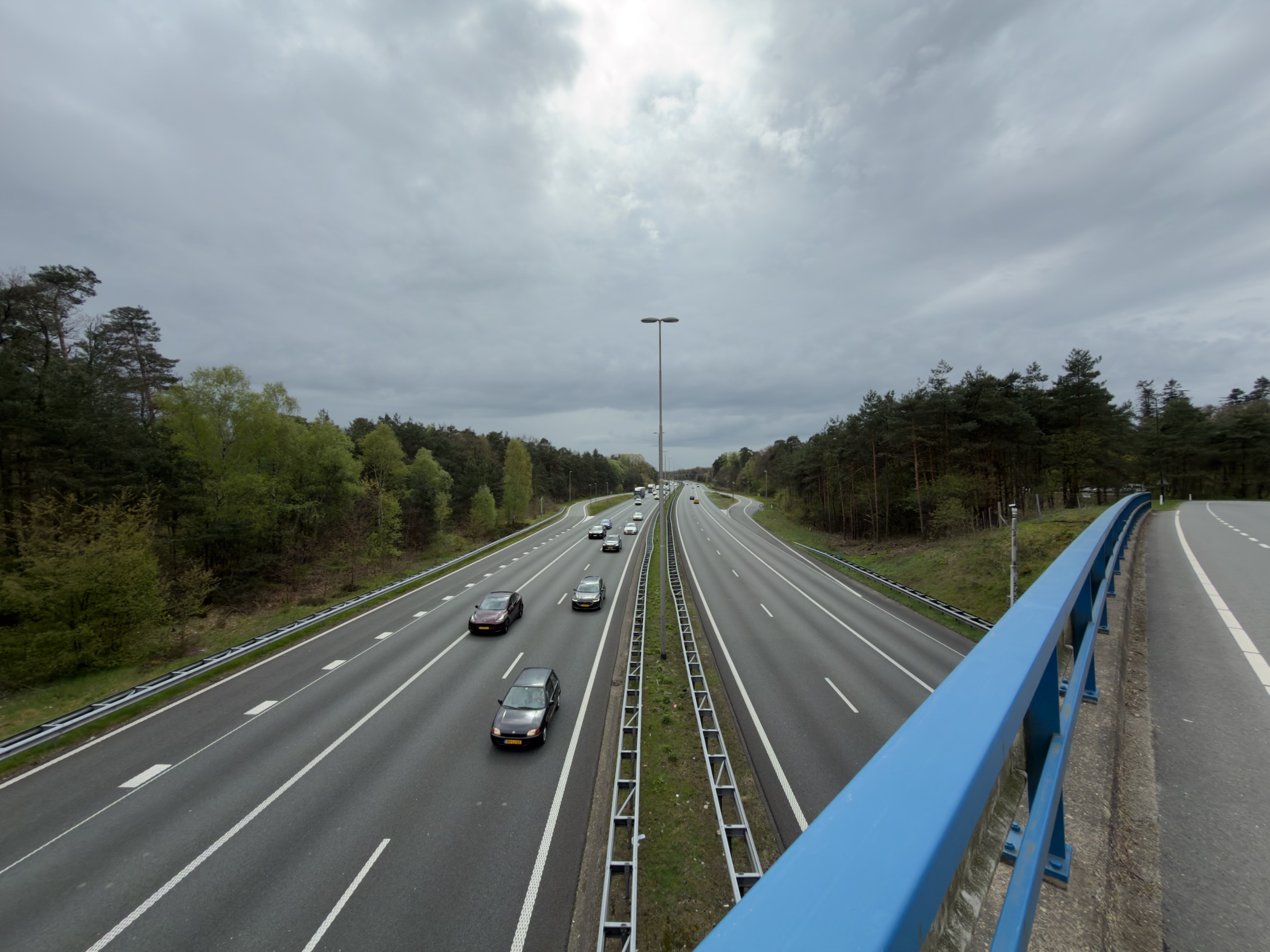 View over the A50 motorway from a bridge with cars passing below and a blue railing